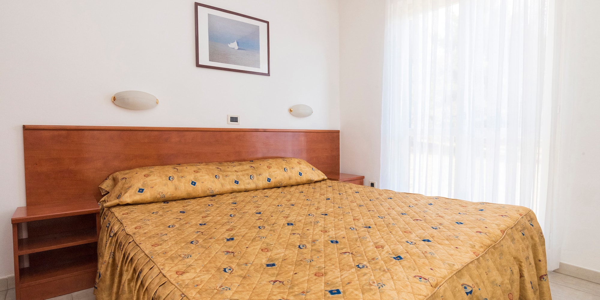 a bed with a gold blanket and a picture on the wall