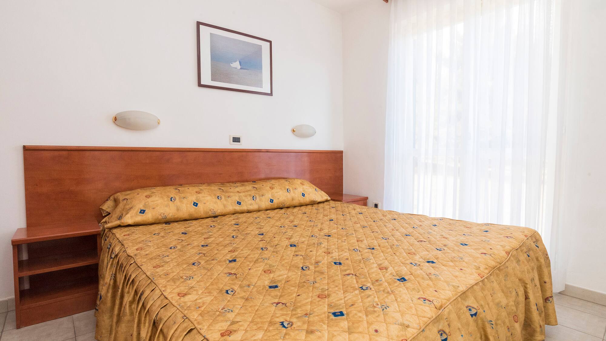 a bed with a gold blanket and a picture on the wall