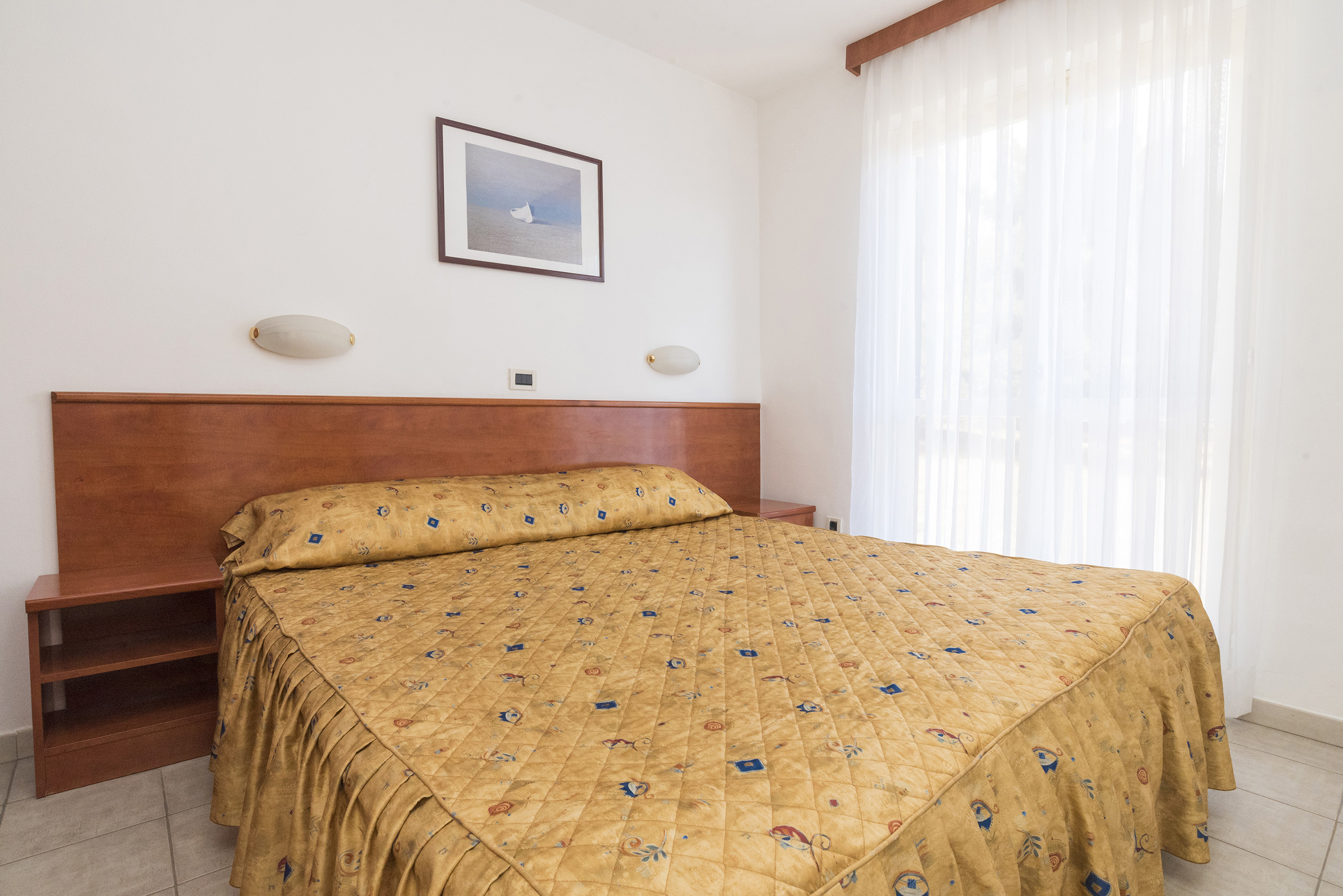 a bed with a gold blanket and a picture on the wall