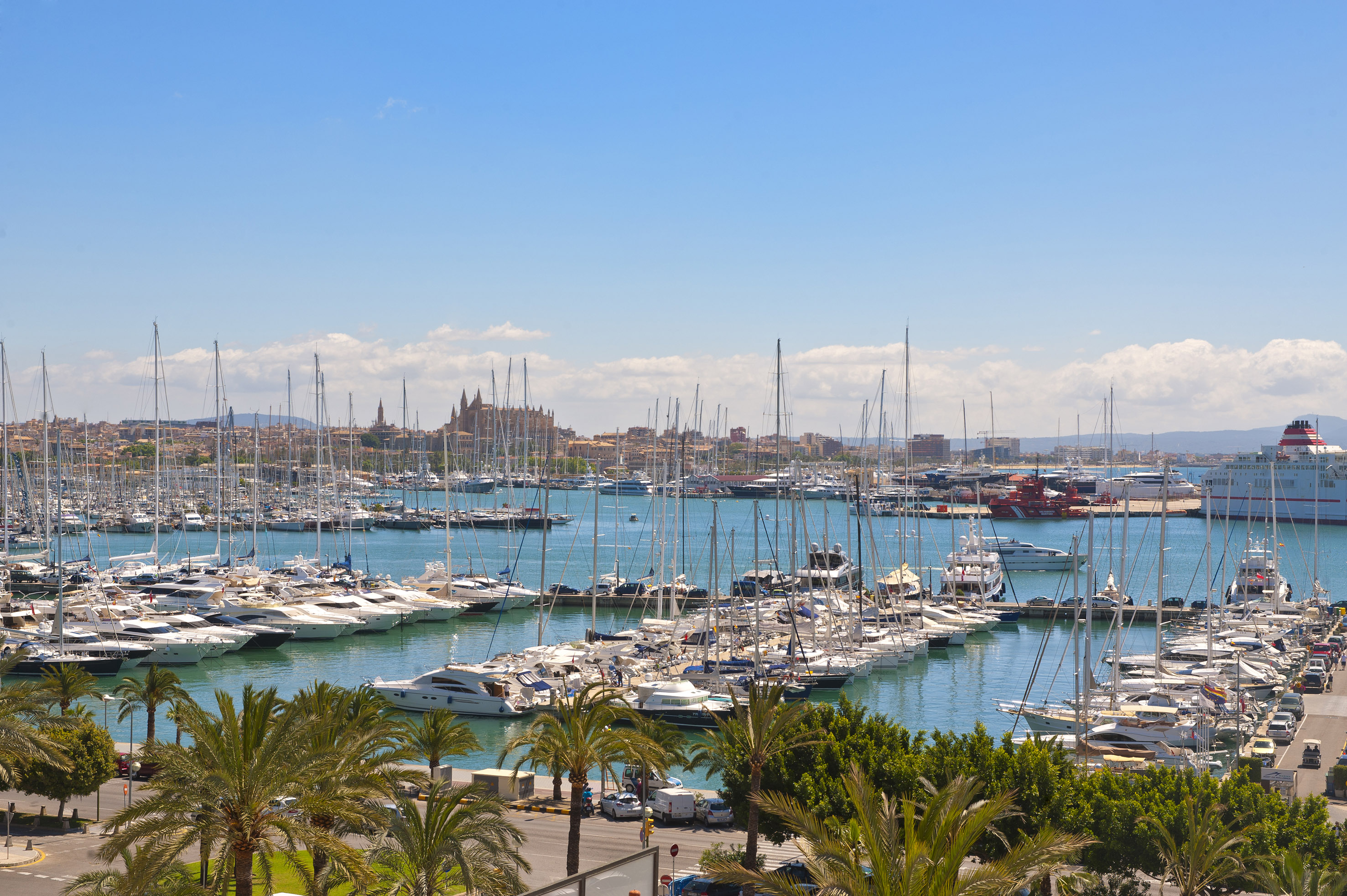 Palma de Mallorca marina with yachts, sailboats, city skyline, and cathedral.