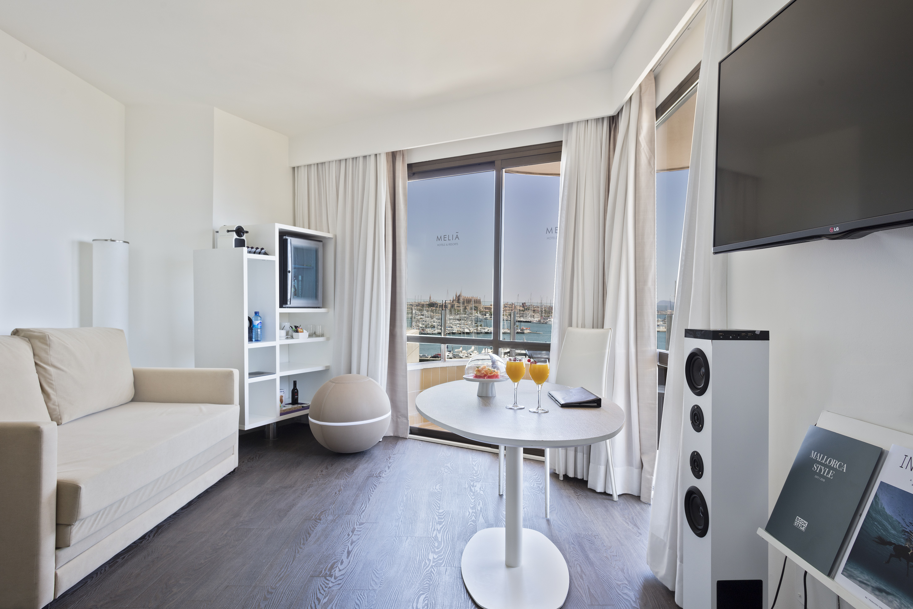 Meliã hotel suite with marina view balcony, sofa, and dining area.