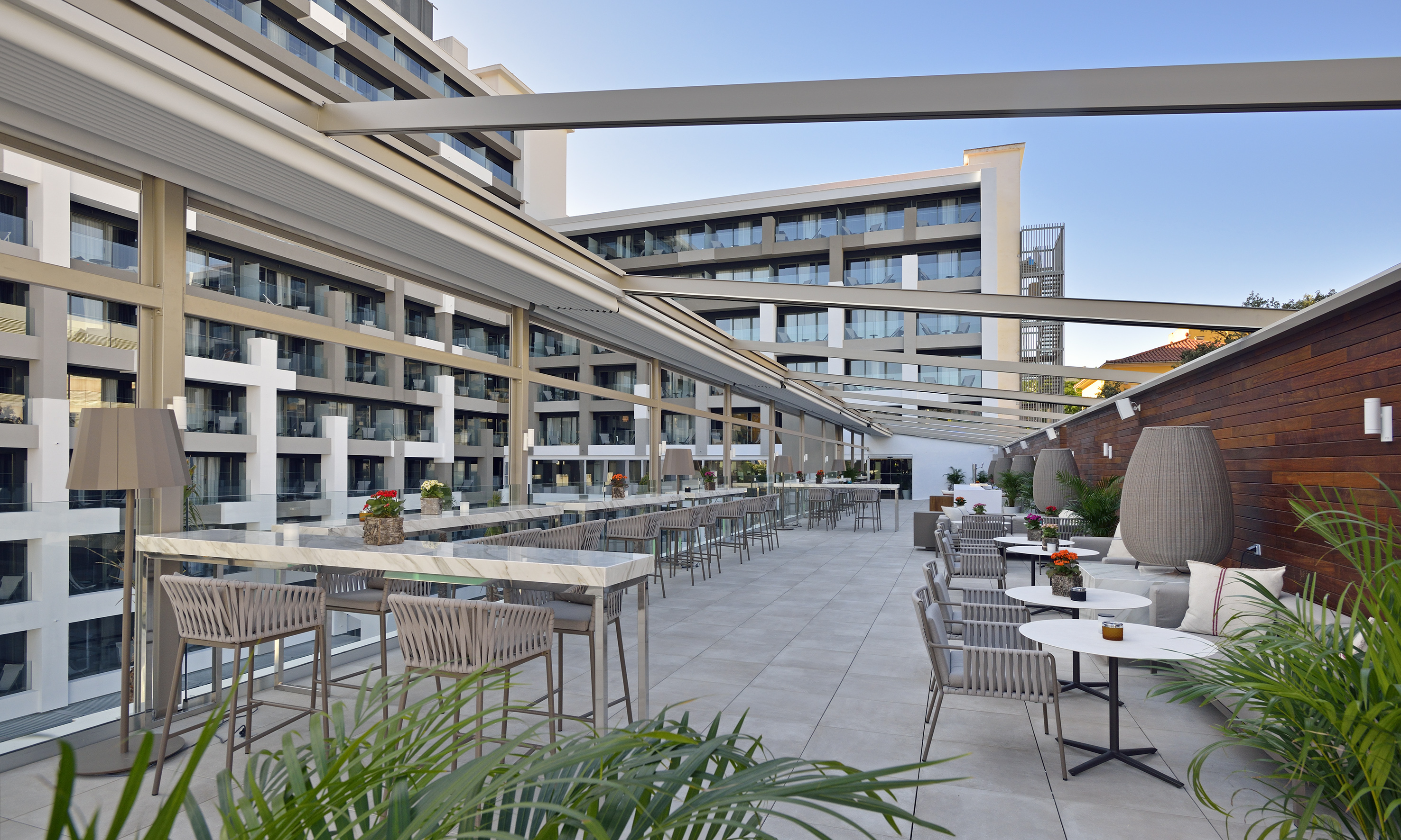 Modern hotel rooftop bar with stylish lounge seating and high tables.