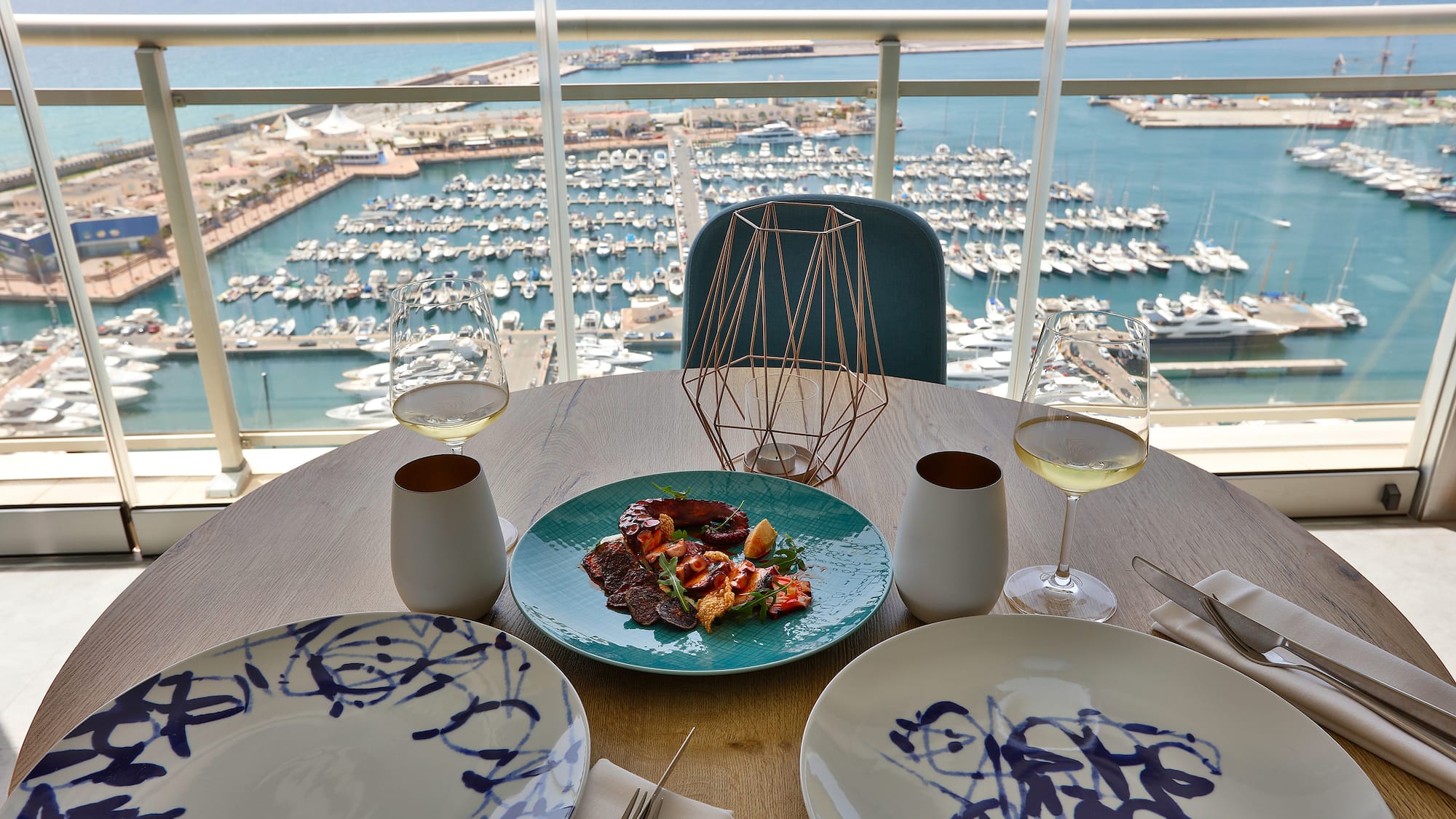 a table with plates and glasses on it and a view of a marina