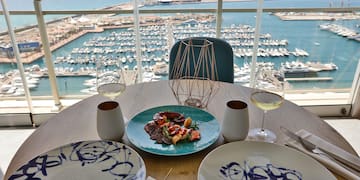 a table with plates and glasses on it and a view of a marina