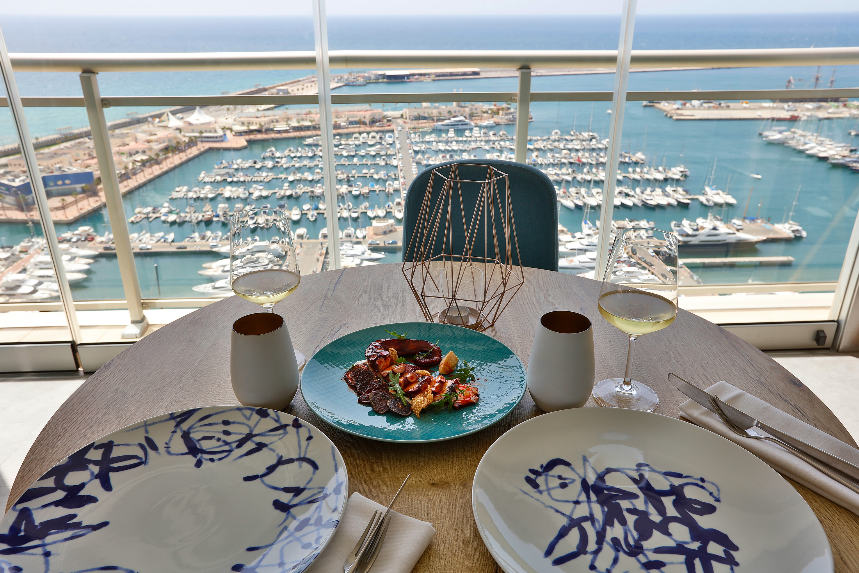 a table with plates and glasses on it and a view of a marina