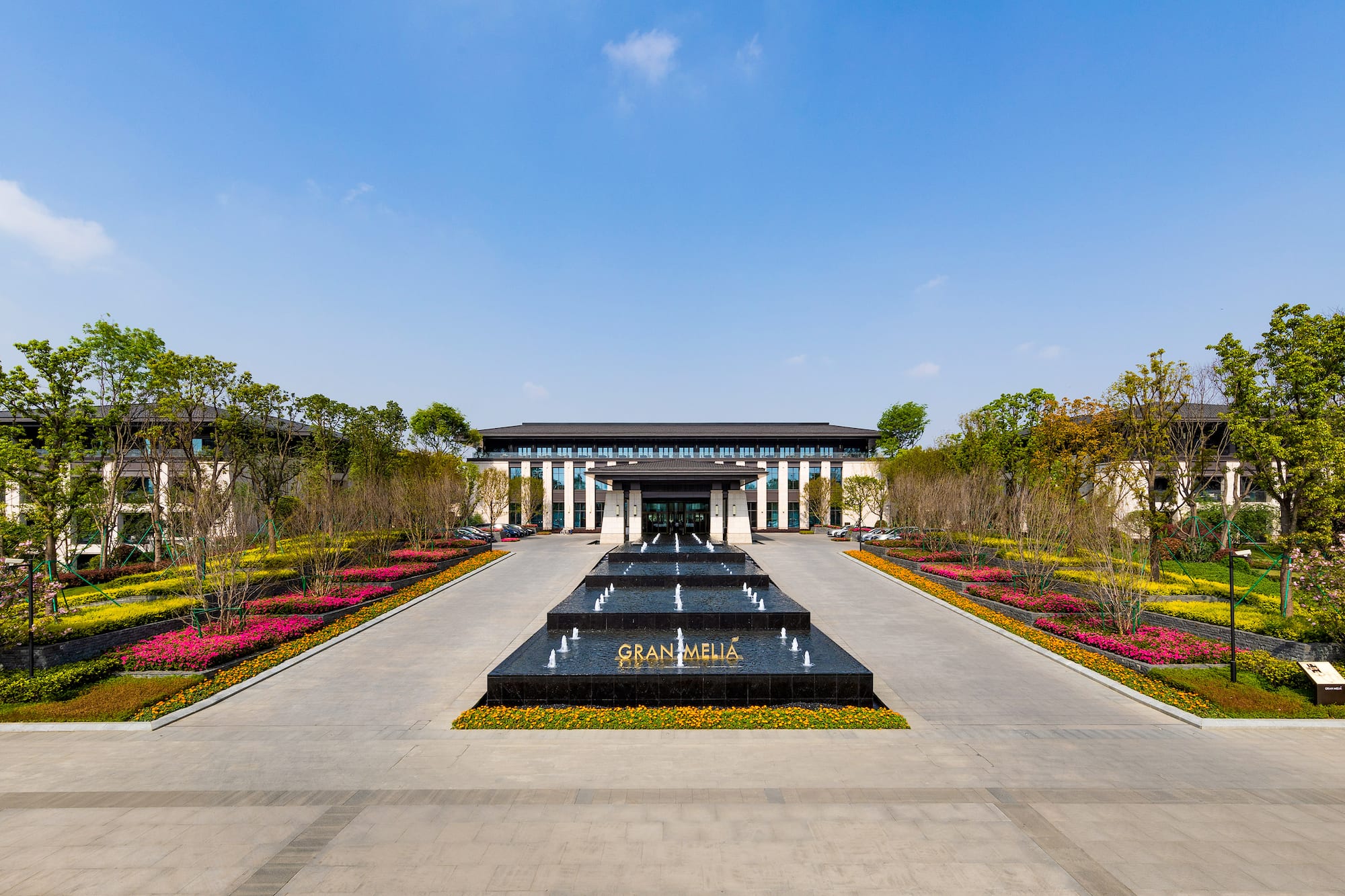 Gran Melia hotel entrance with tiered fountain and vibrant flower gardens.
