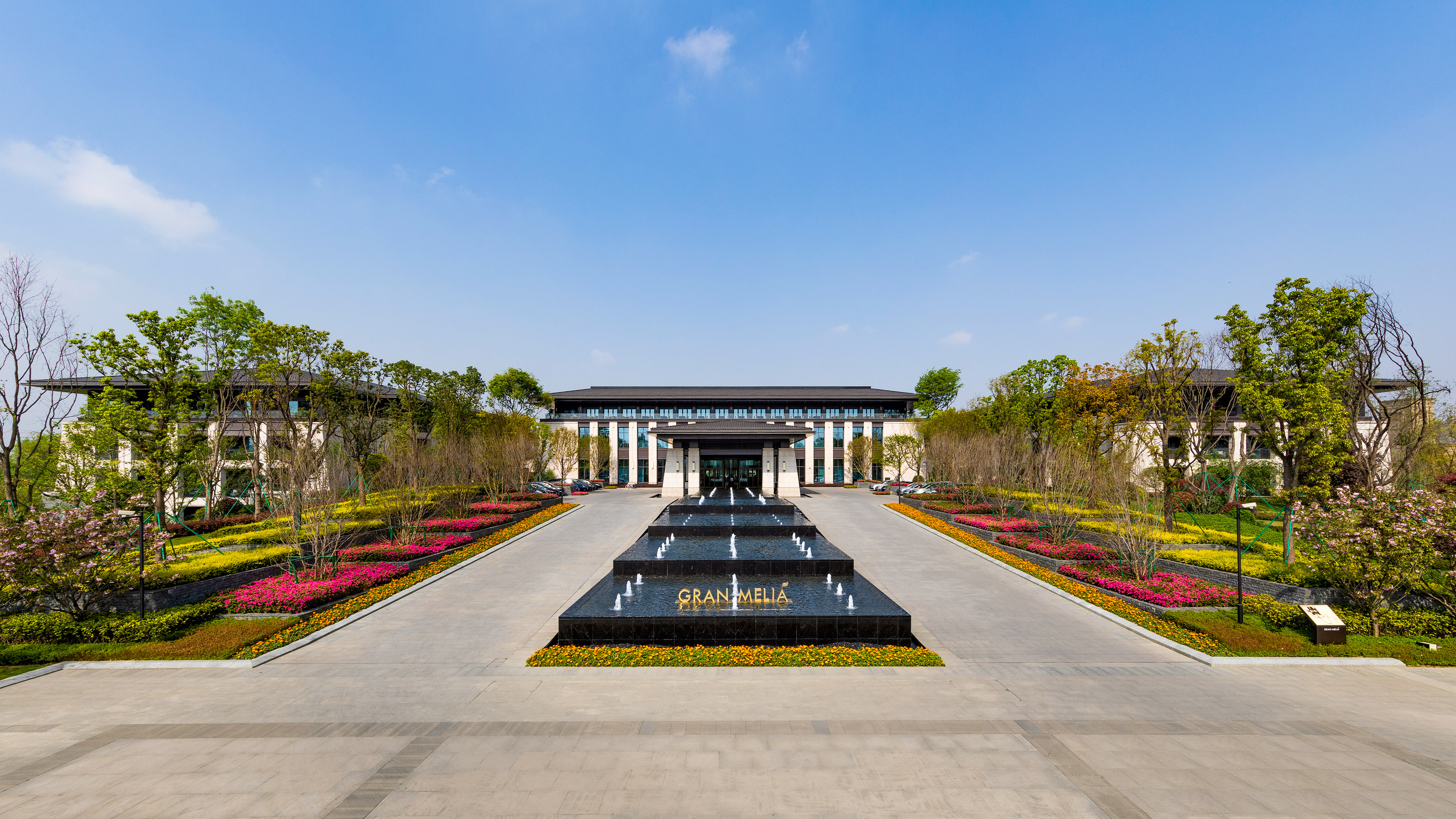 Gran Melia hotel entrance with tiered fountain and vibrant flower gardens.