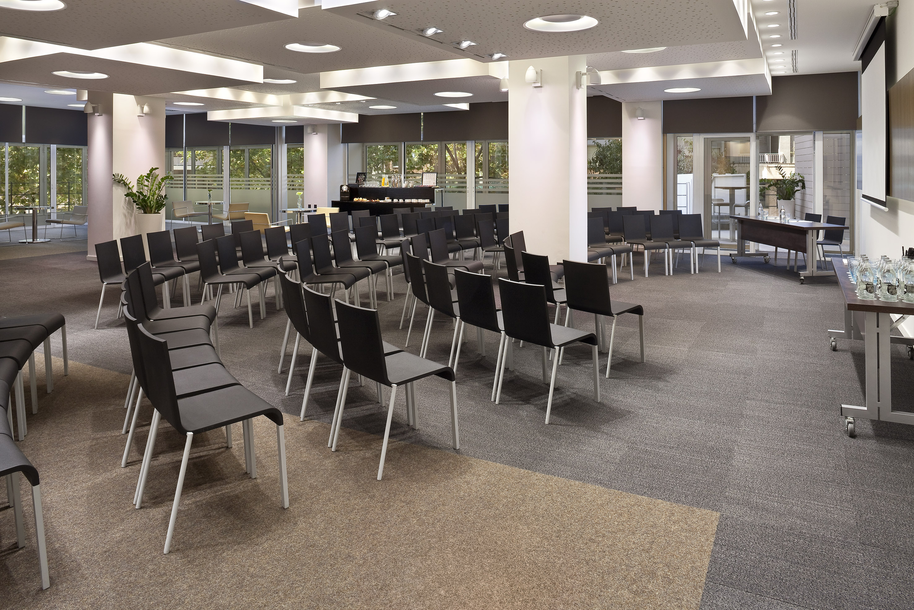 Modern conference room with black chairs, projector screen, and large windows.