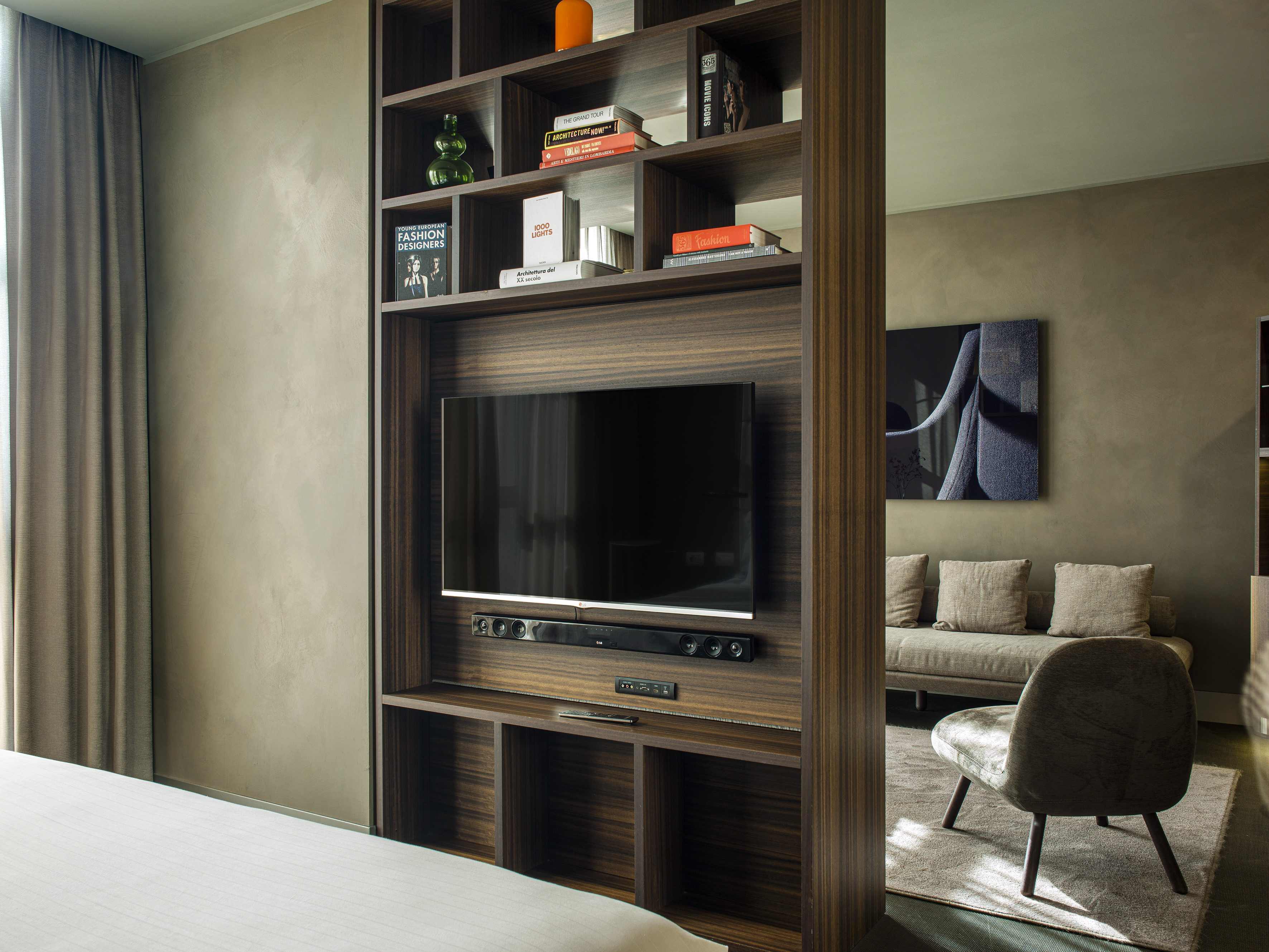 Contemporary room: dark wood media console with TV, books, sofa, and bed.