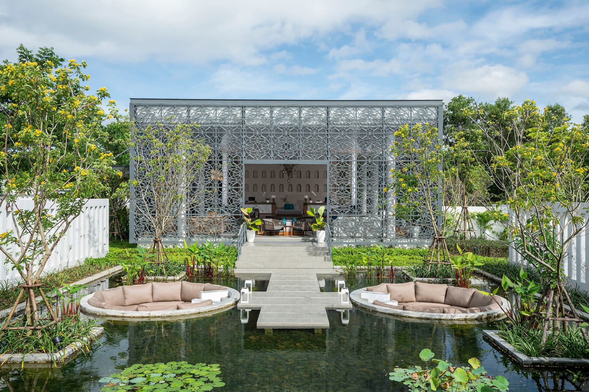 Geometric building with reflecting pond and circular outdoor lounge seating.