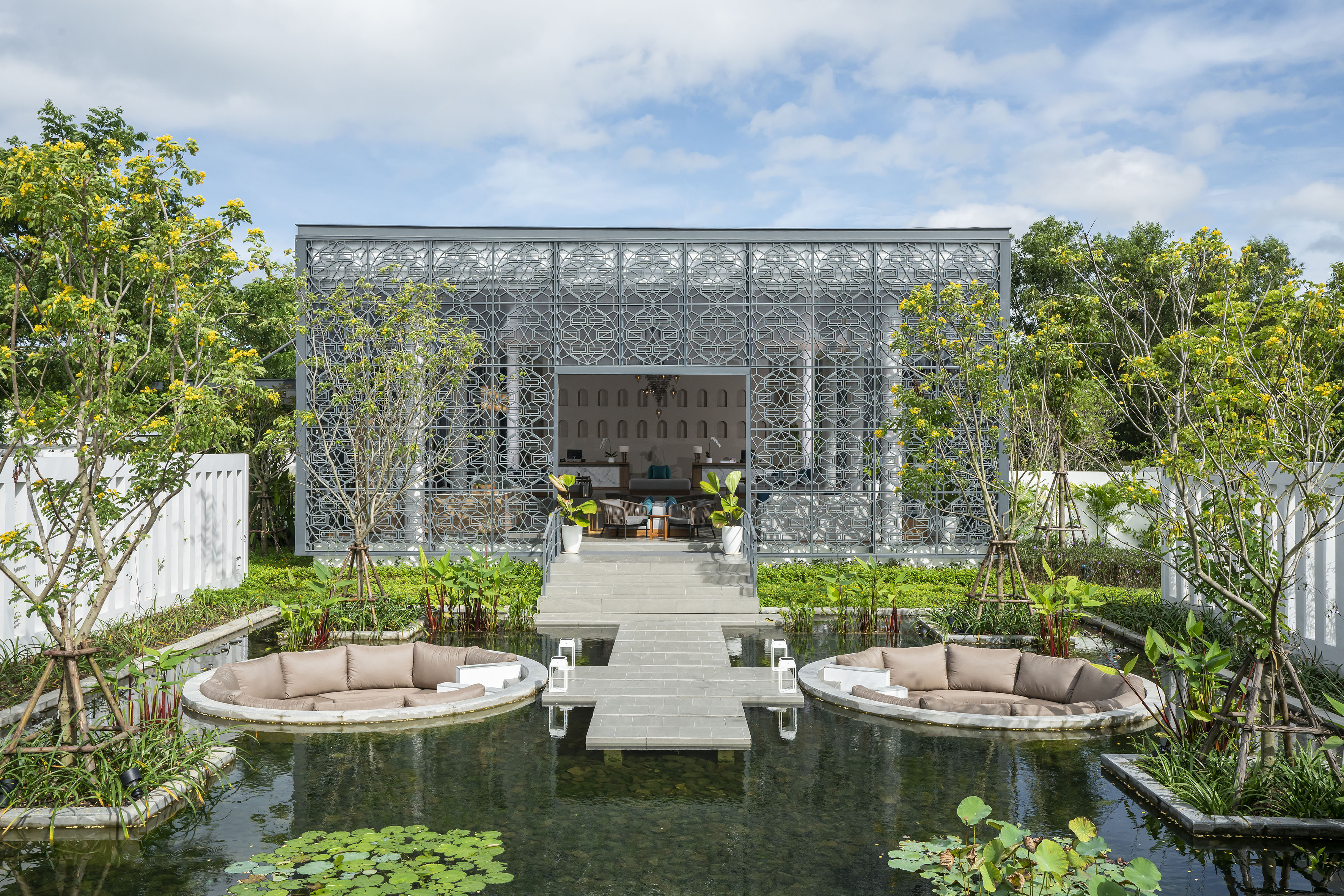 Geometric building with reflecting pond and circular outdoor lounge seating.