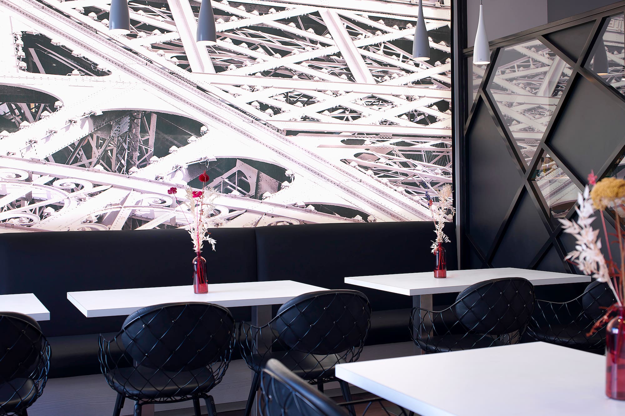 Parisian-themed cafe with Eiffel Tower mural, black chairs, white tables.