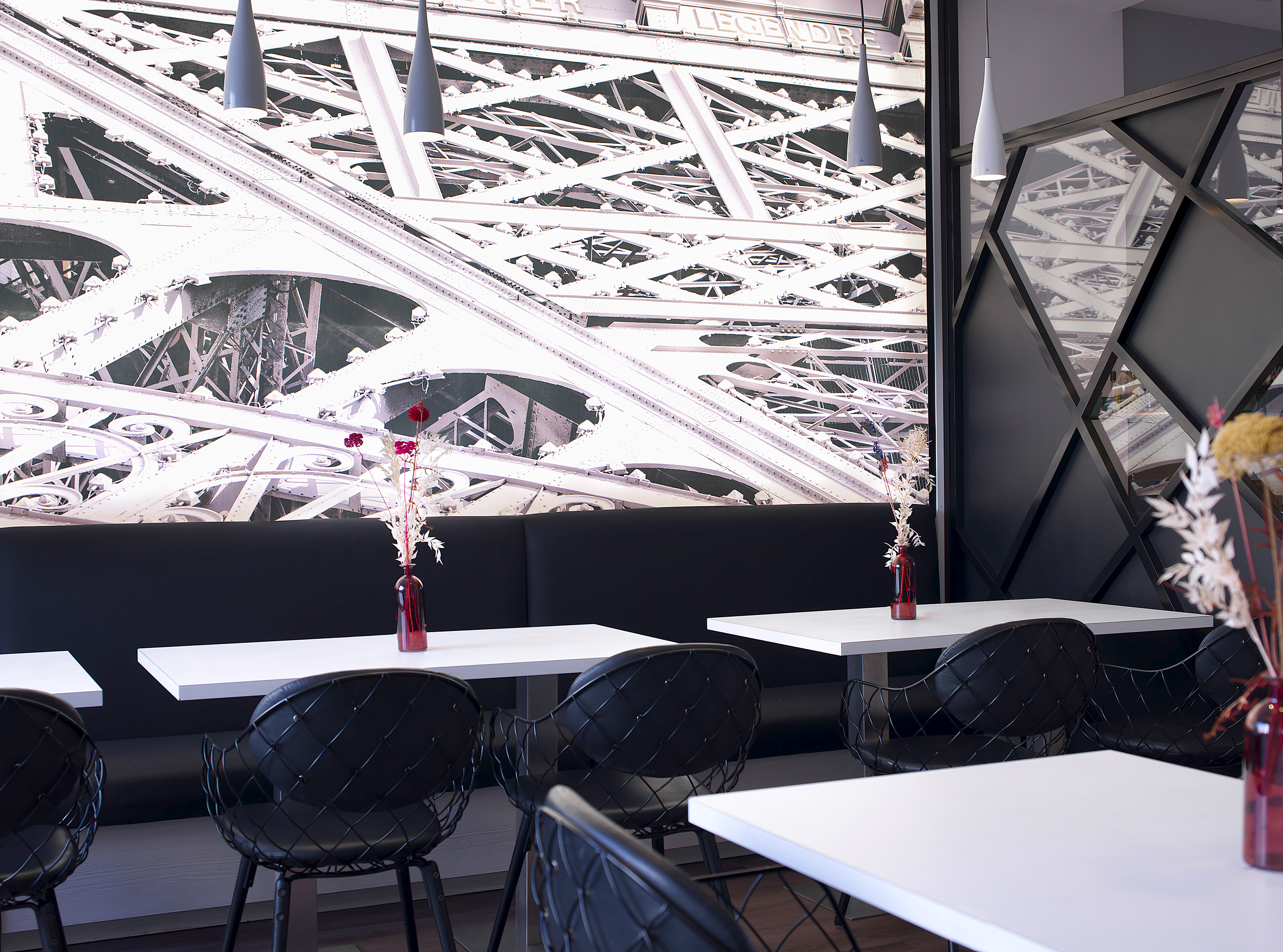 Parisian-themed cafe with Eiffel Tower mural, black chairs, white tables.