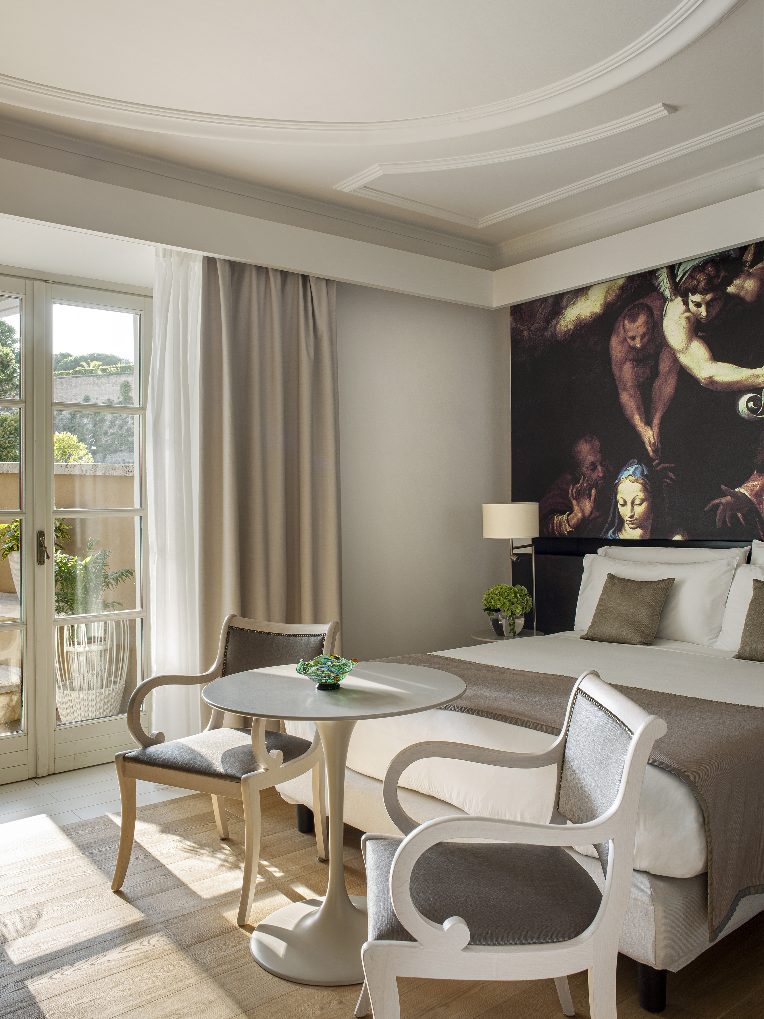 Luxury suite with classical mural, balcony access, and cozy seating.