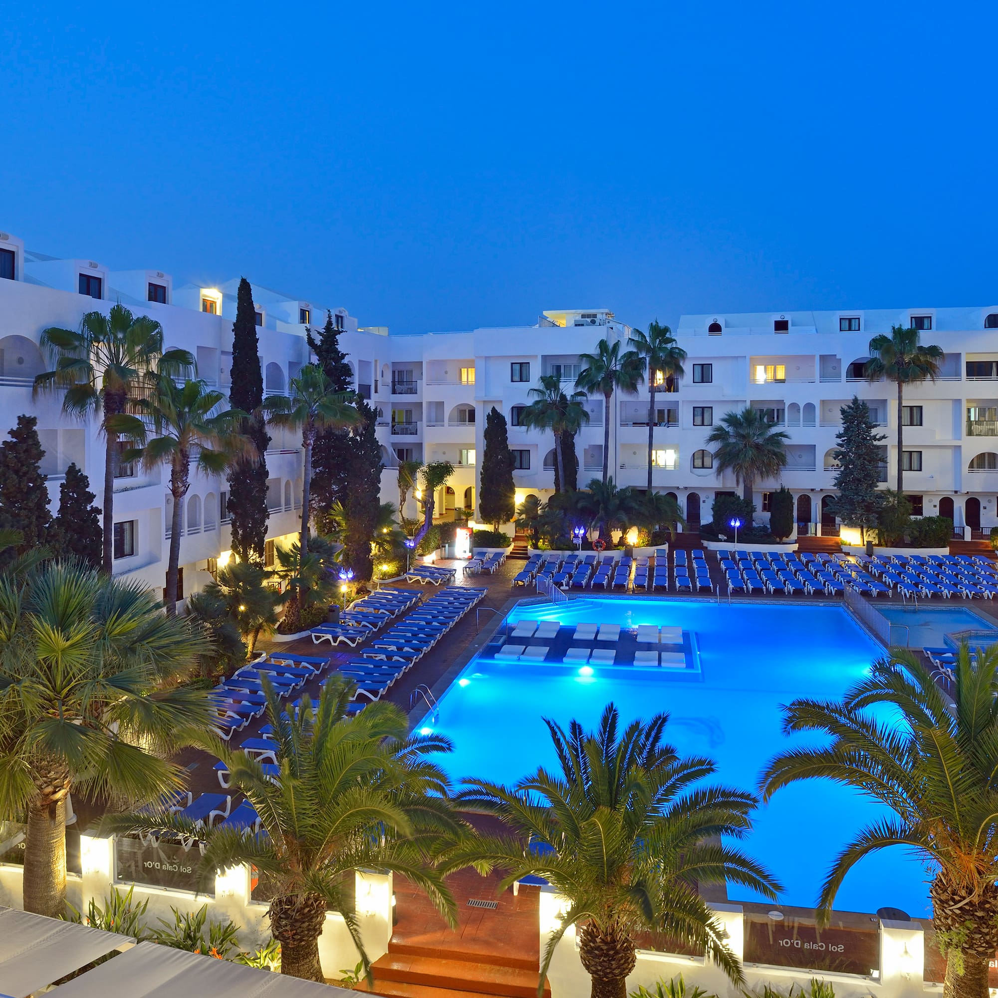 a pool and palm trees in front of a hotel