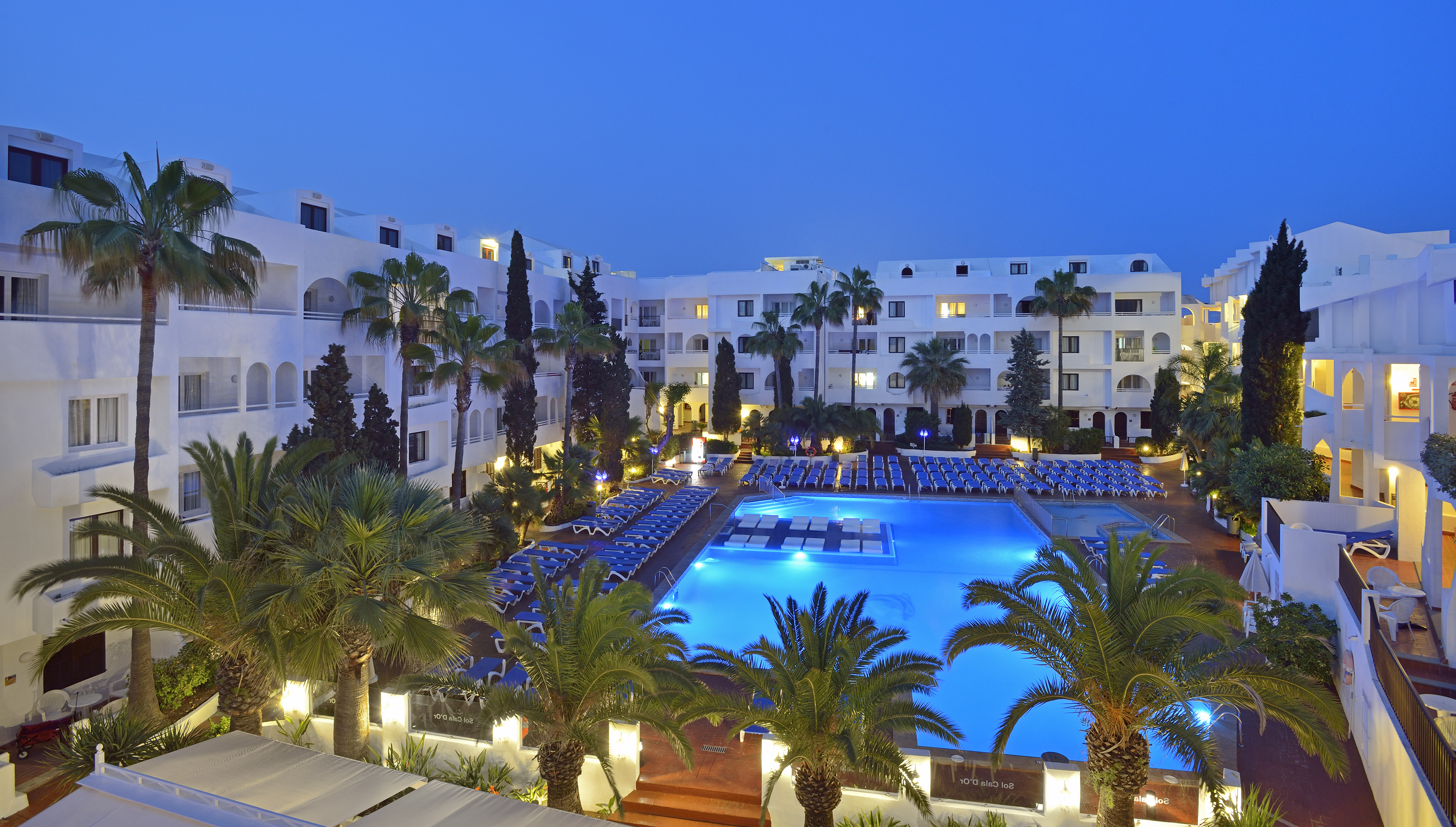 a pool and palm trees in front of a hotel