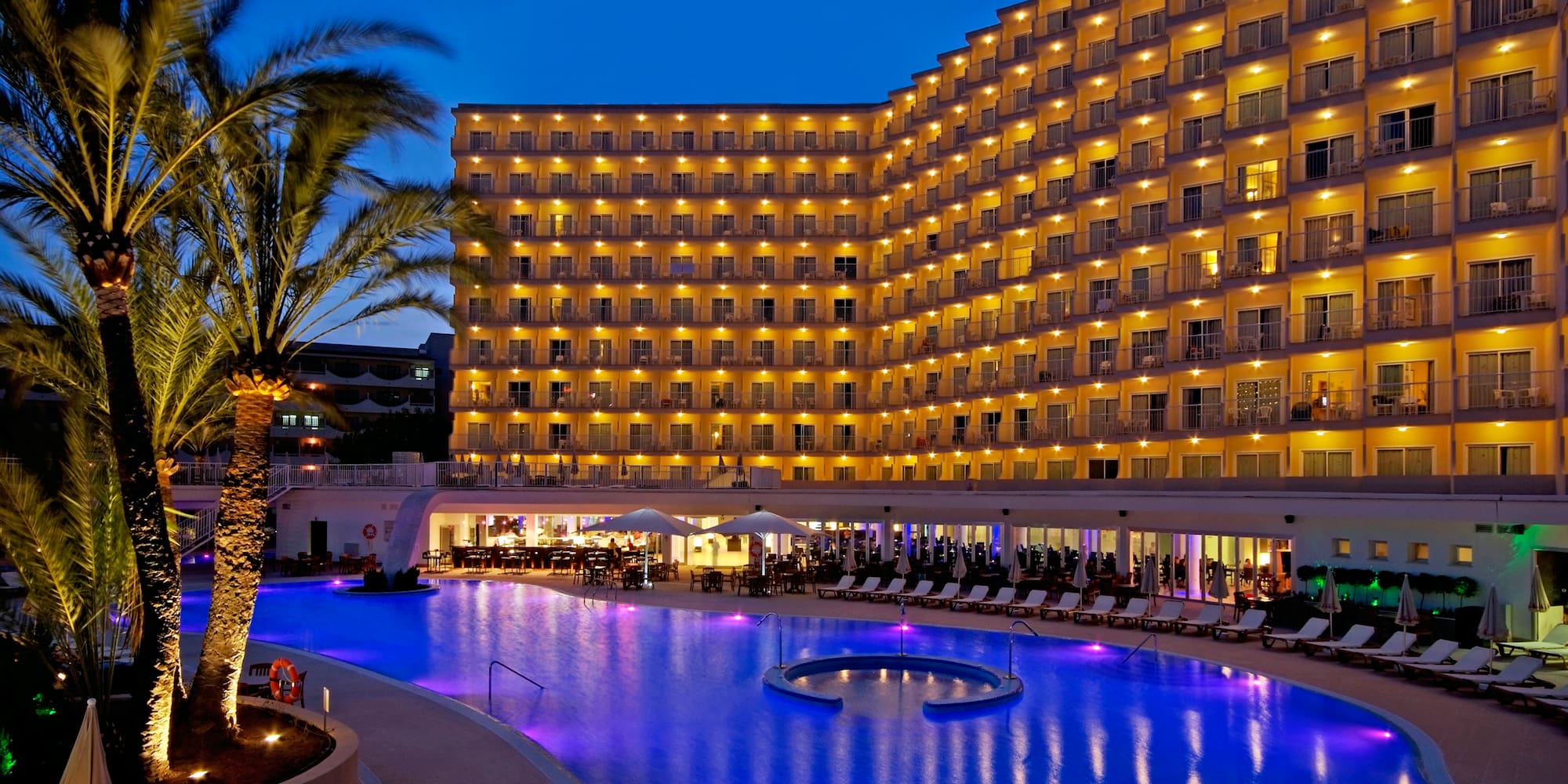 a large hotel with a pool and palm trees