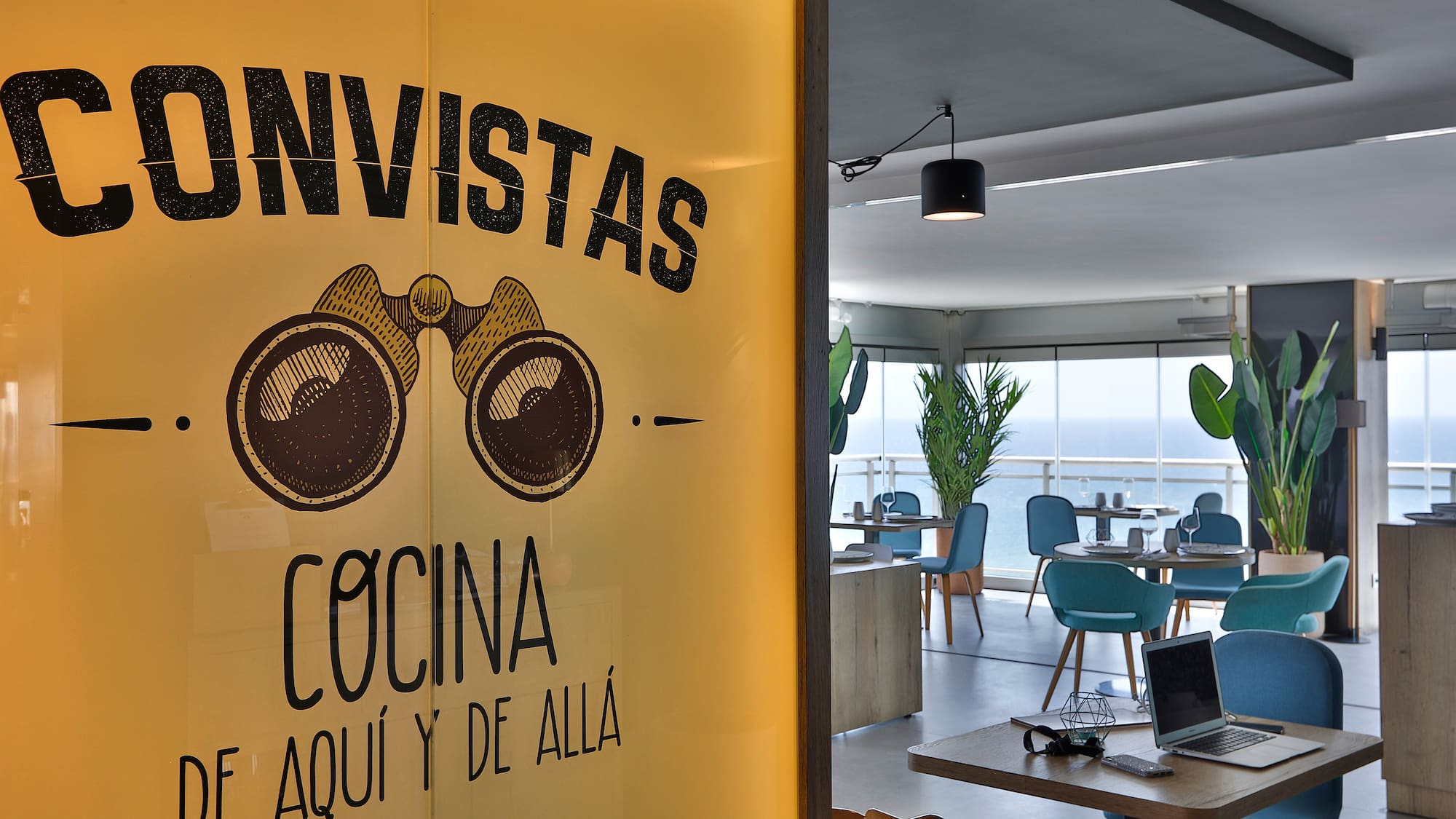 a room with a window with a sign and a laptop and a table