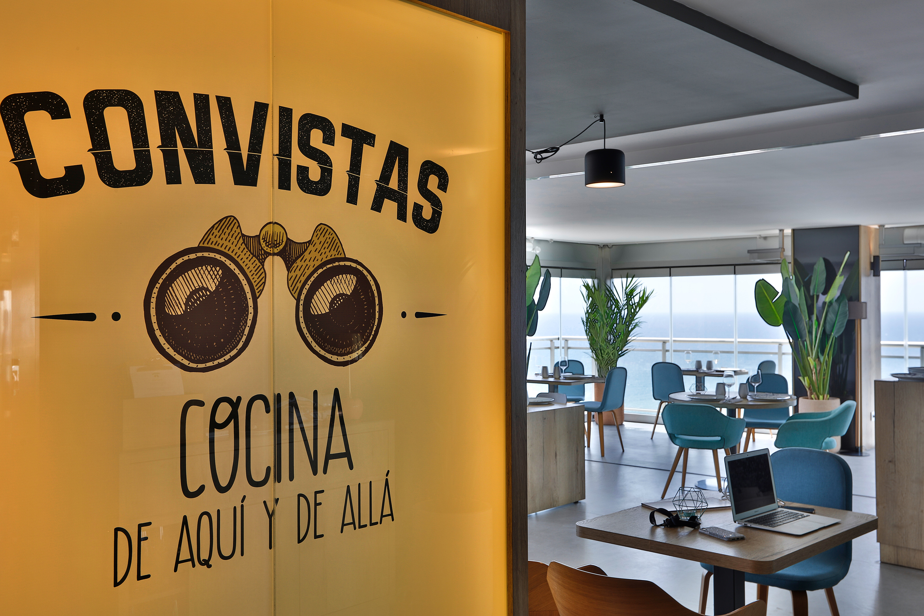 a room with a window with a sign and a laptop and a table