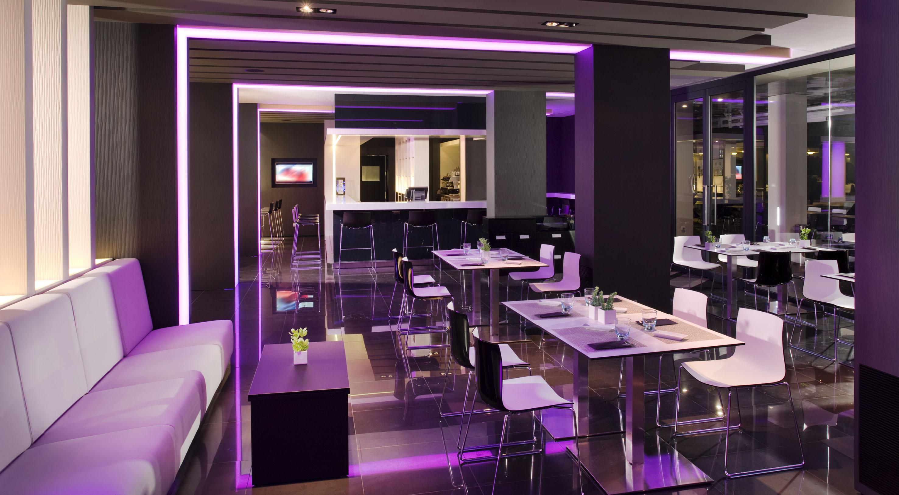 Sleek modern restaurant bar with purple LED lighting and white seating.