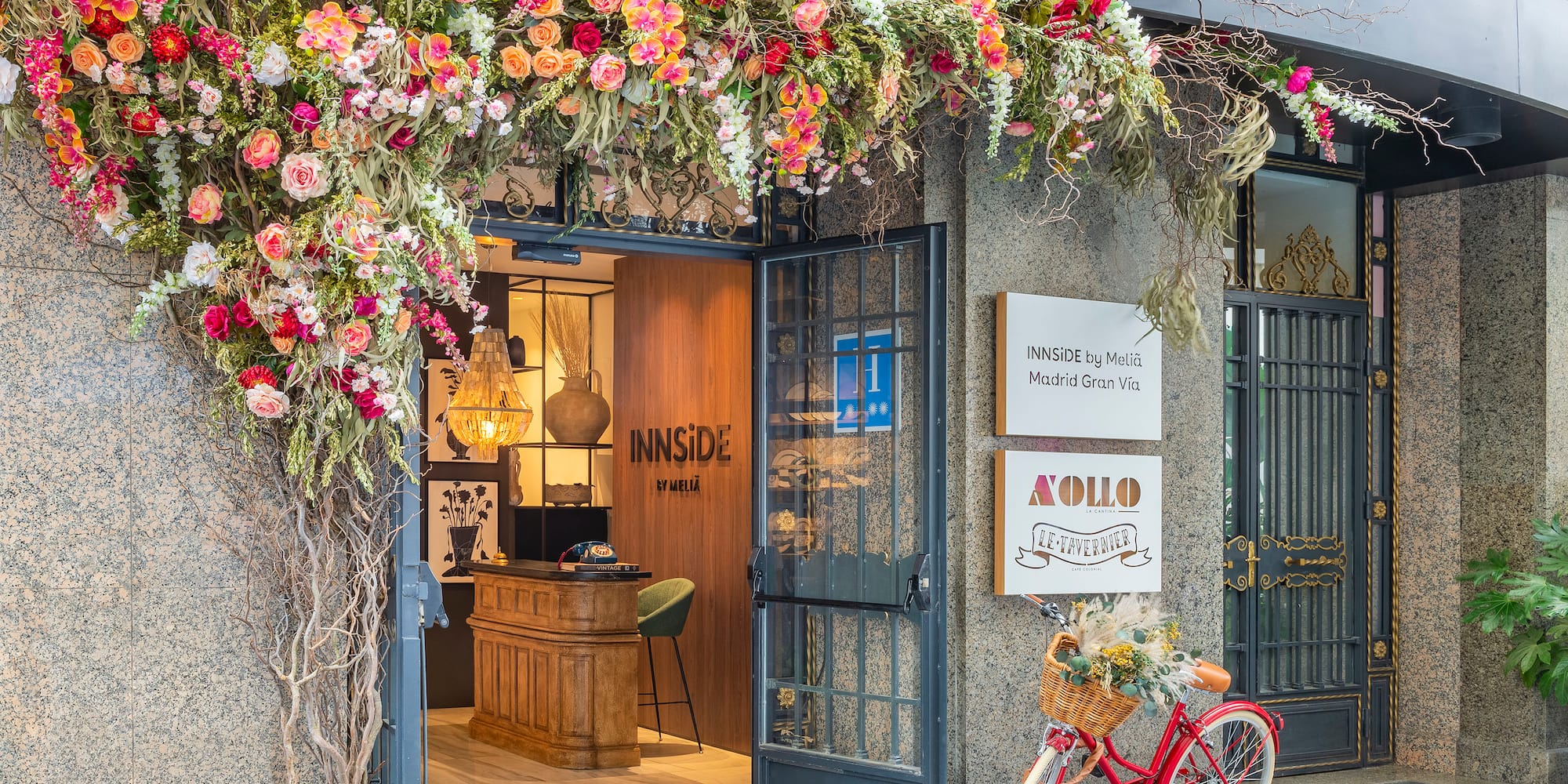INNSIDE Madrid Gran Vía hotel entrance, abundant flowers, red bicycle.