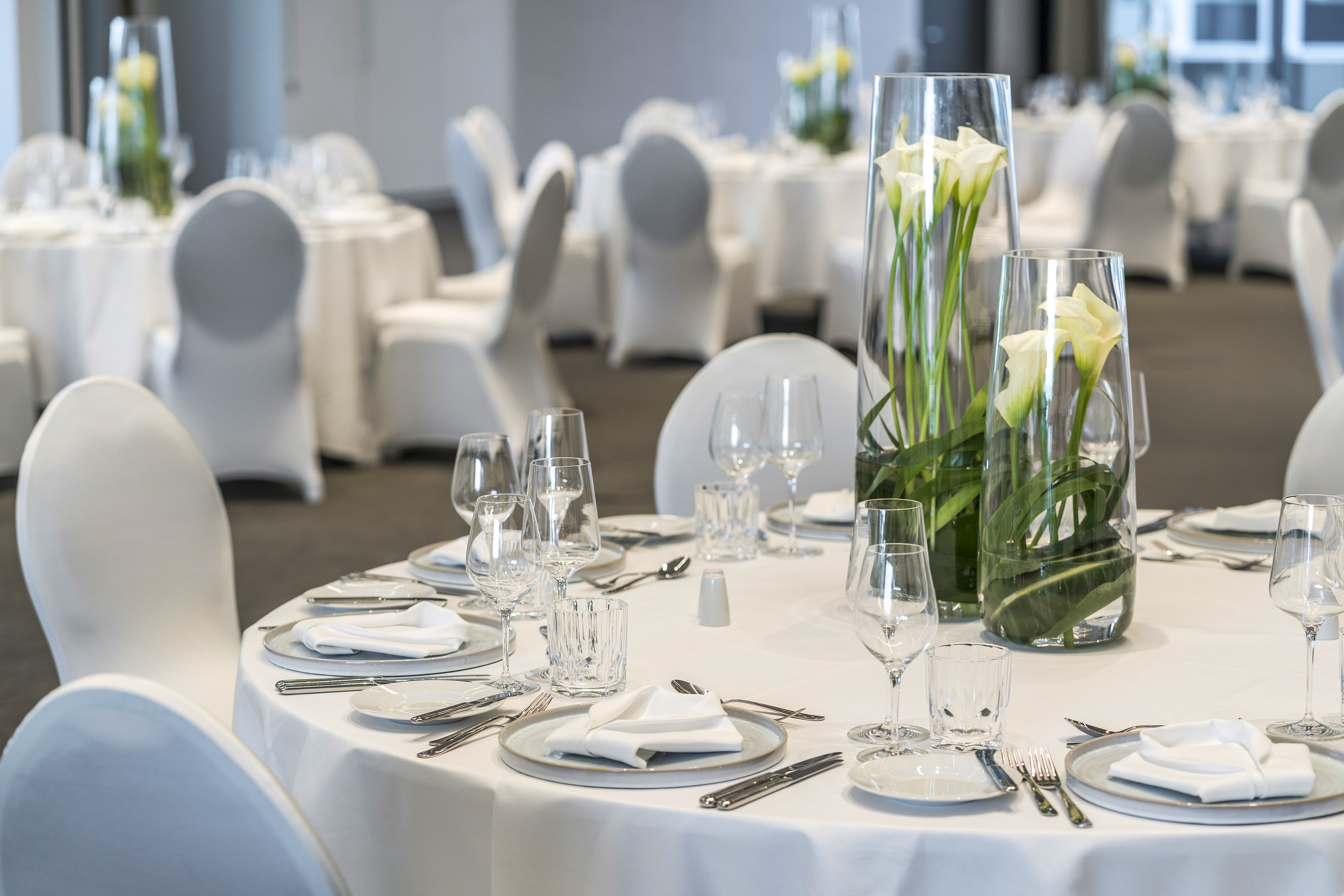 Elegant banquet hall dining tables set with calla lily centerpieces.