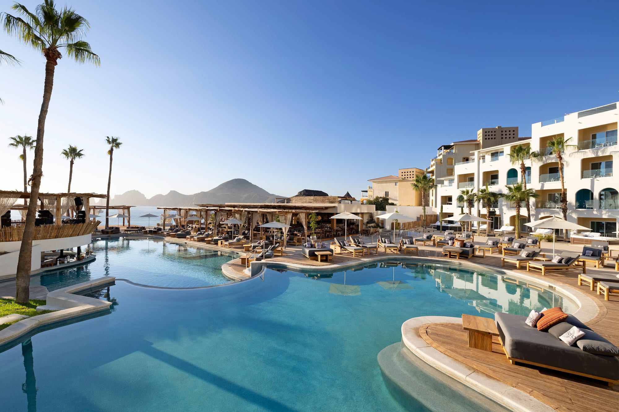 a swimming pool with chairs and a building in the background