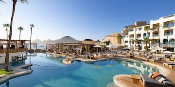 a swimming pool with chairs and a building in the background