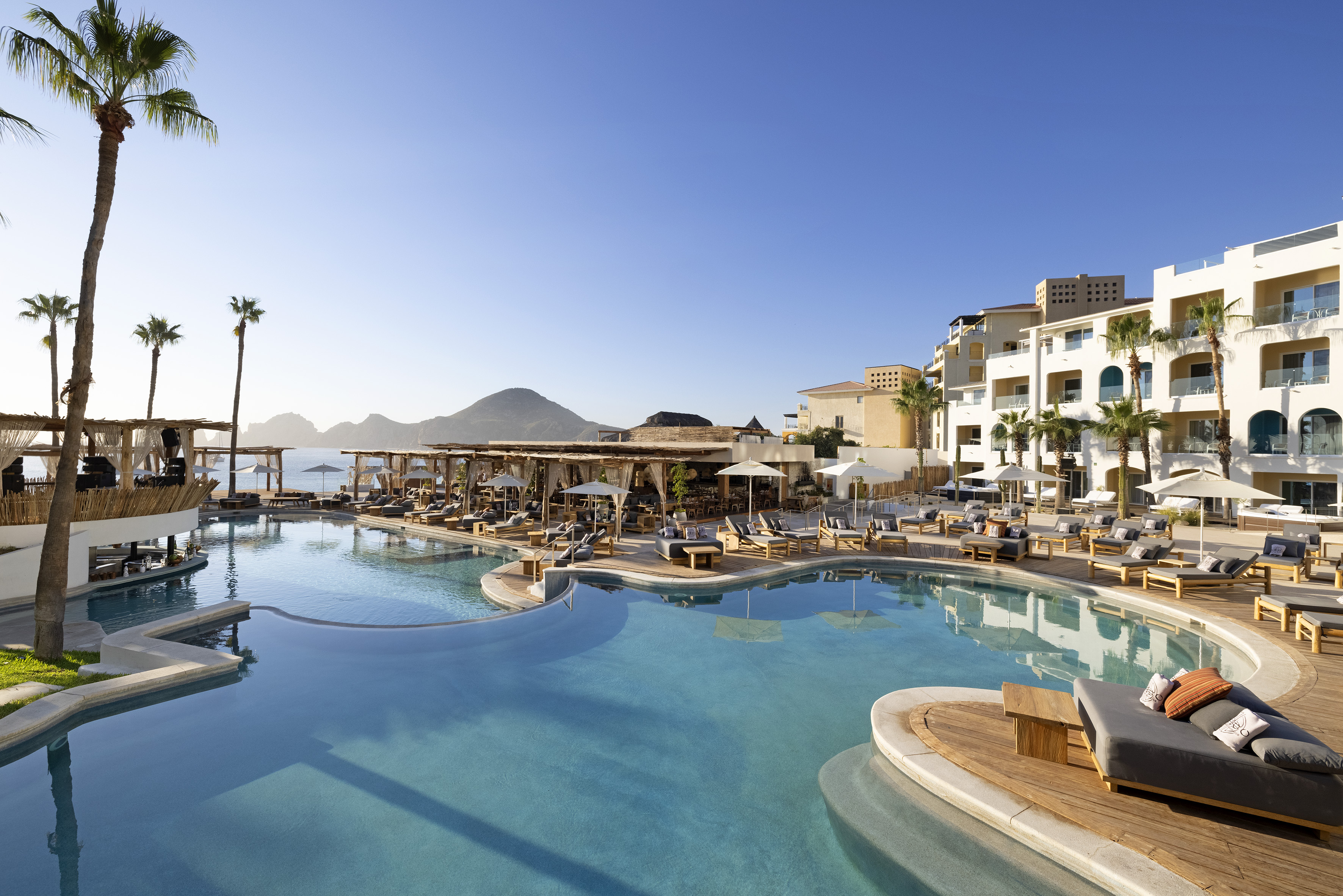 a swimming pool with chairs and a building in the background