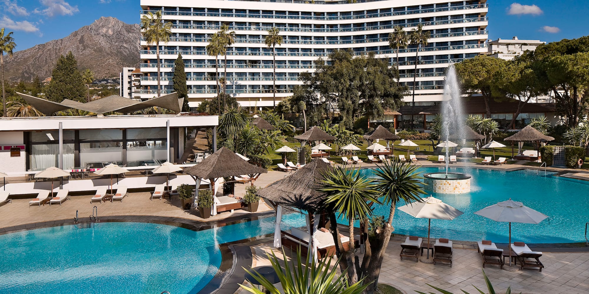 a pool with a fountain in front of a large building