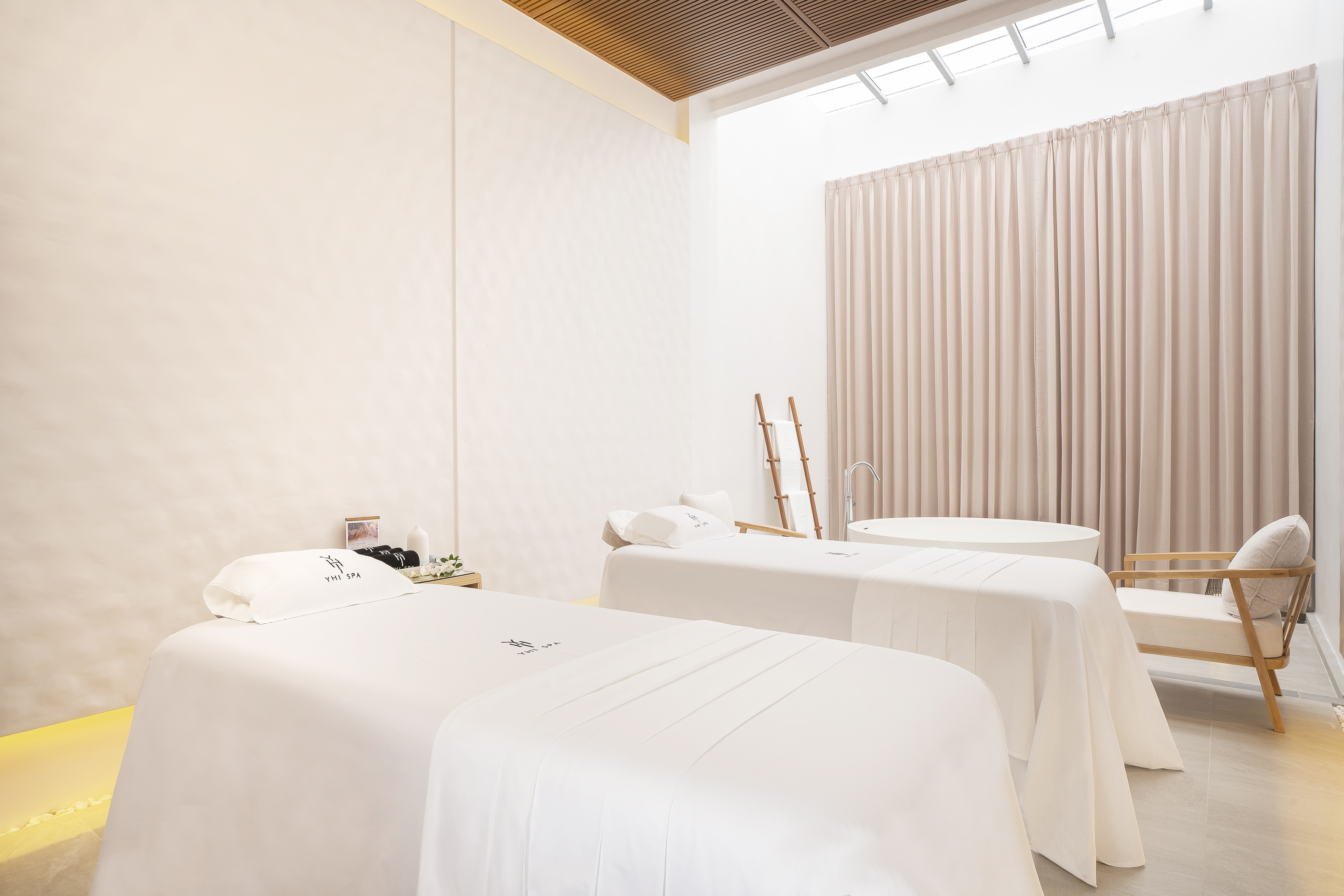 Serene YHI SPA massage room with twin beds, private bathtub, and natural light.