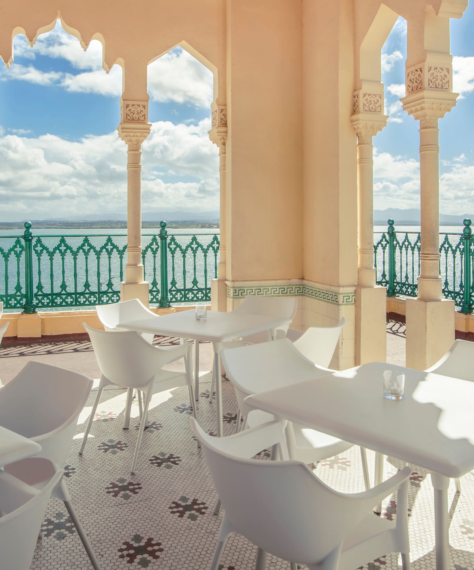 a white tables and chairs on a patio with a green railing