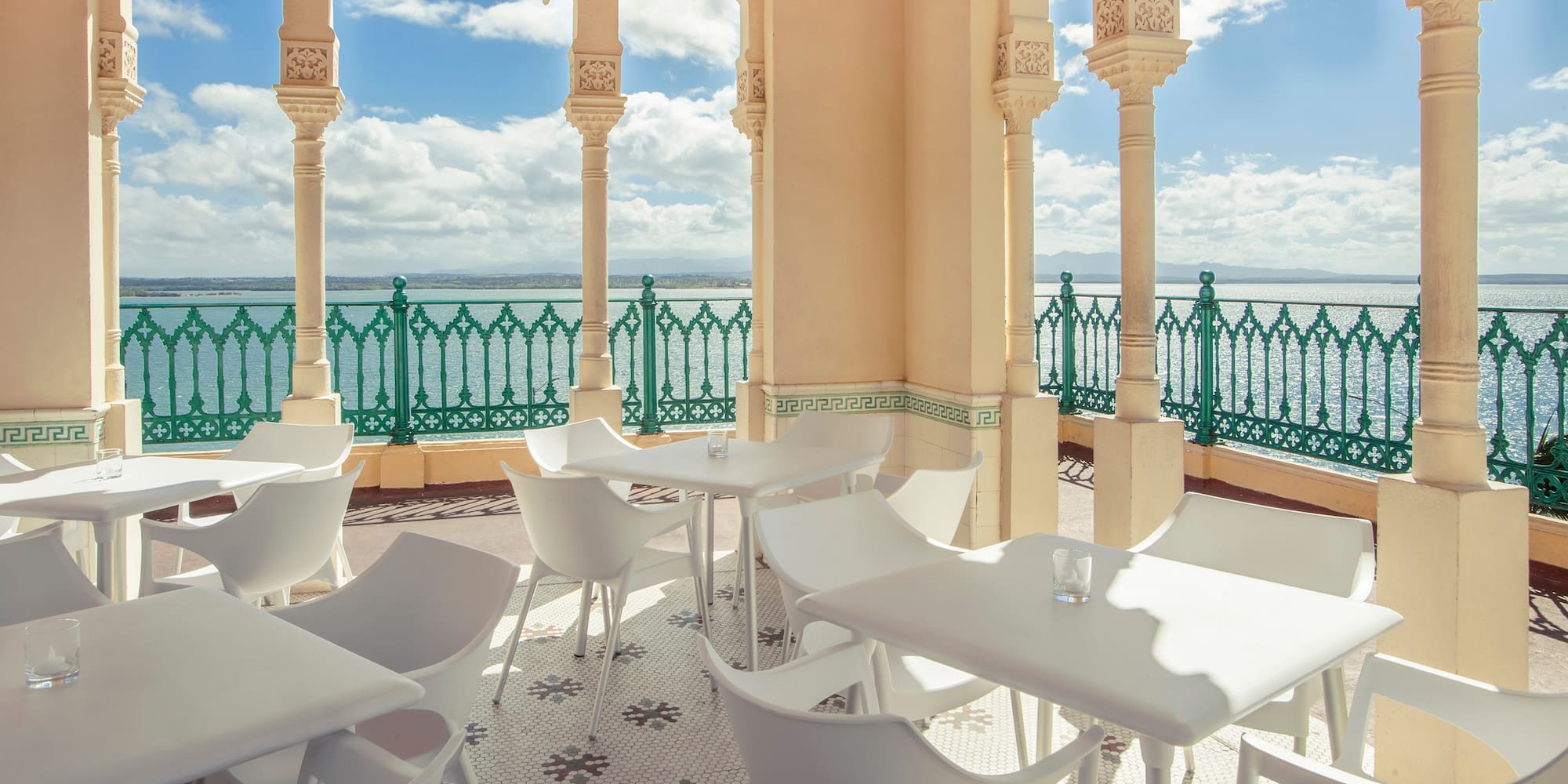 a white tables and chairs on a patio with a green railing