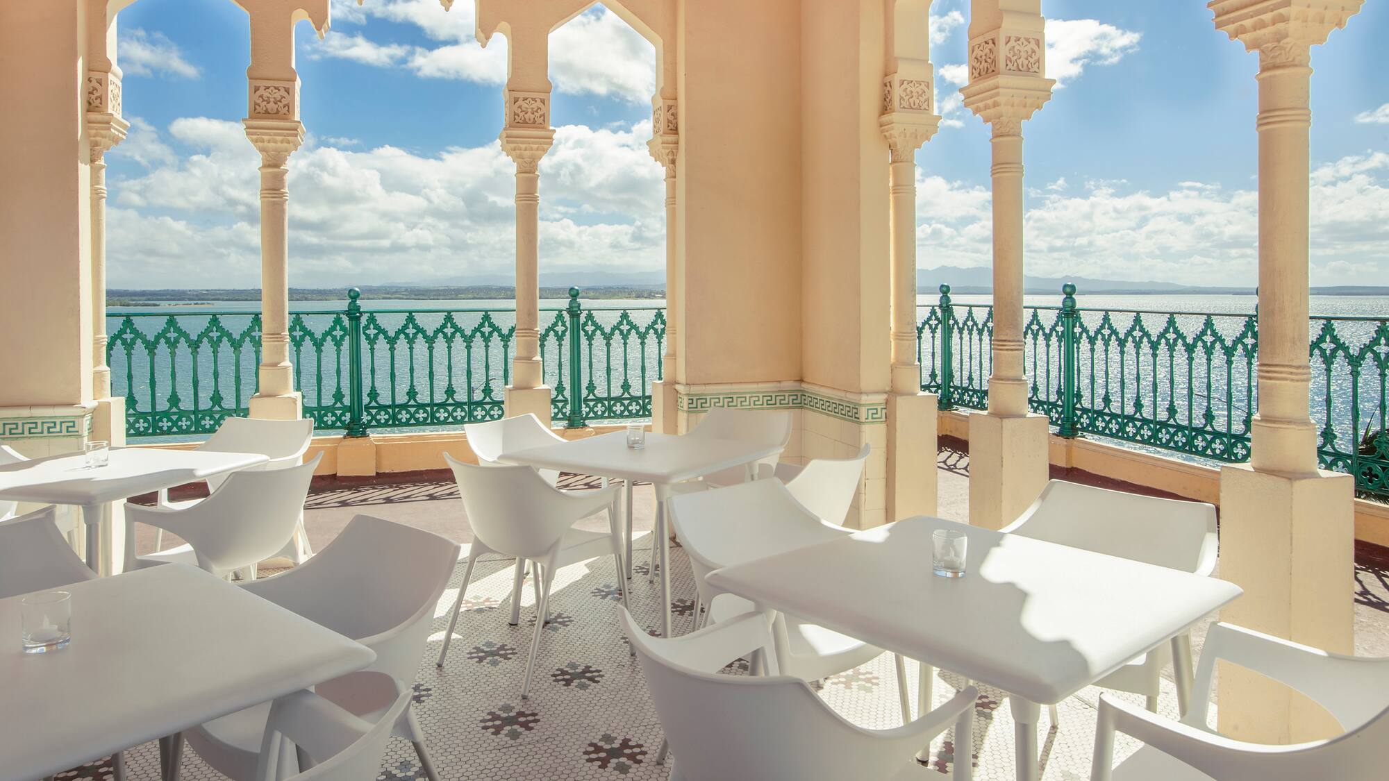 a white tables and chairs on a patio with a green railing