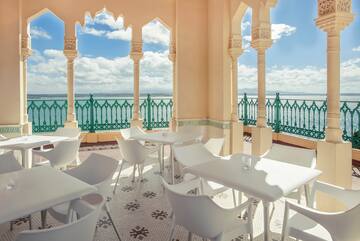 a white tables and chairs on a patio with a green railing