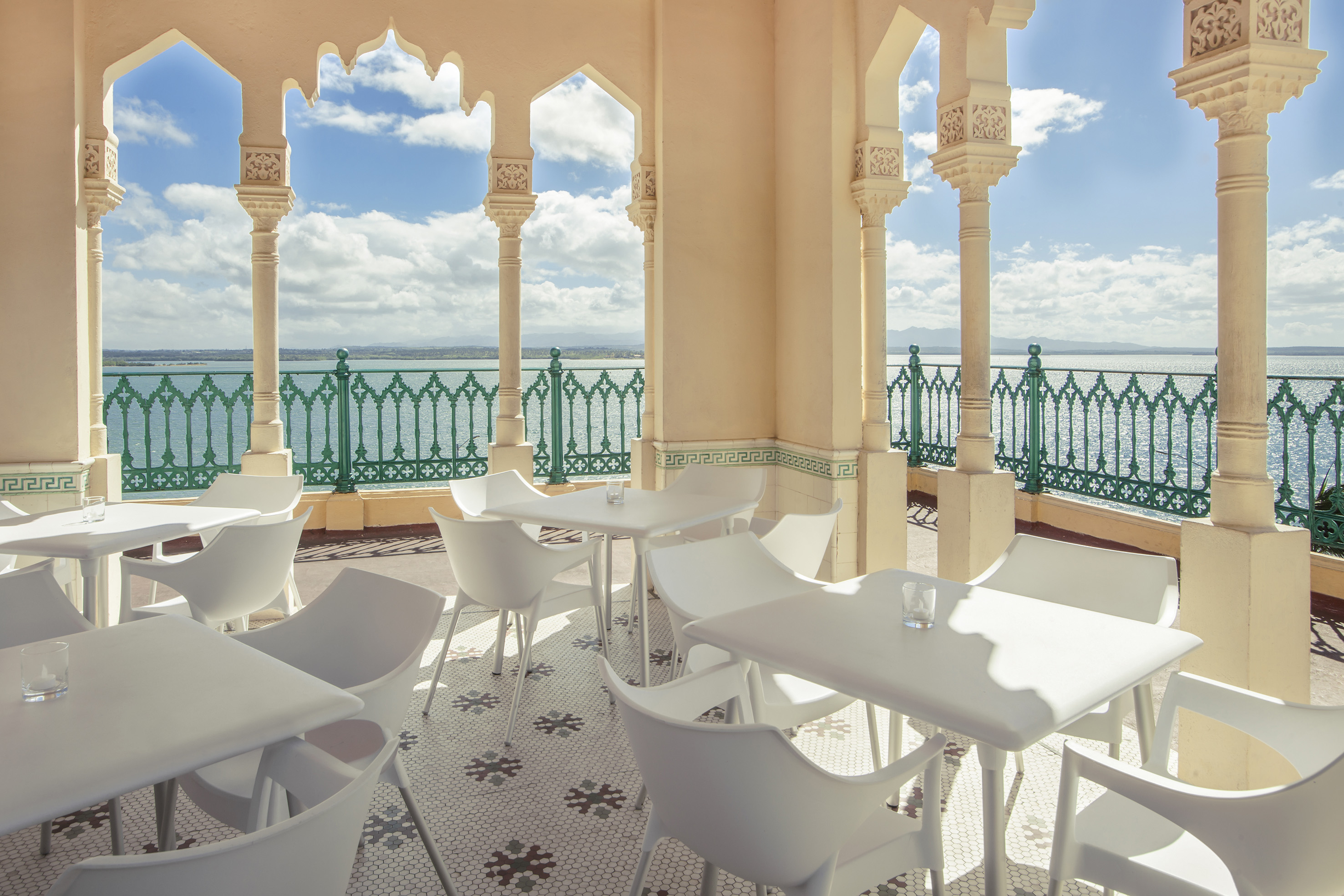 a white tables and chairs on a patio with a green railing
