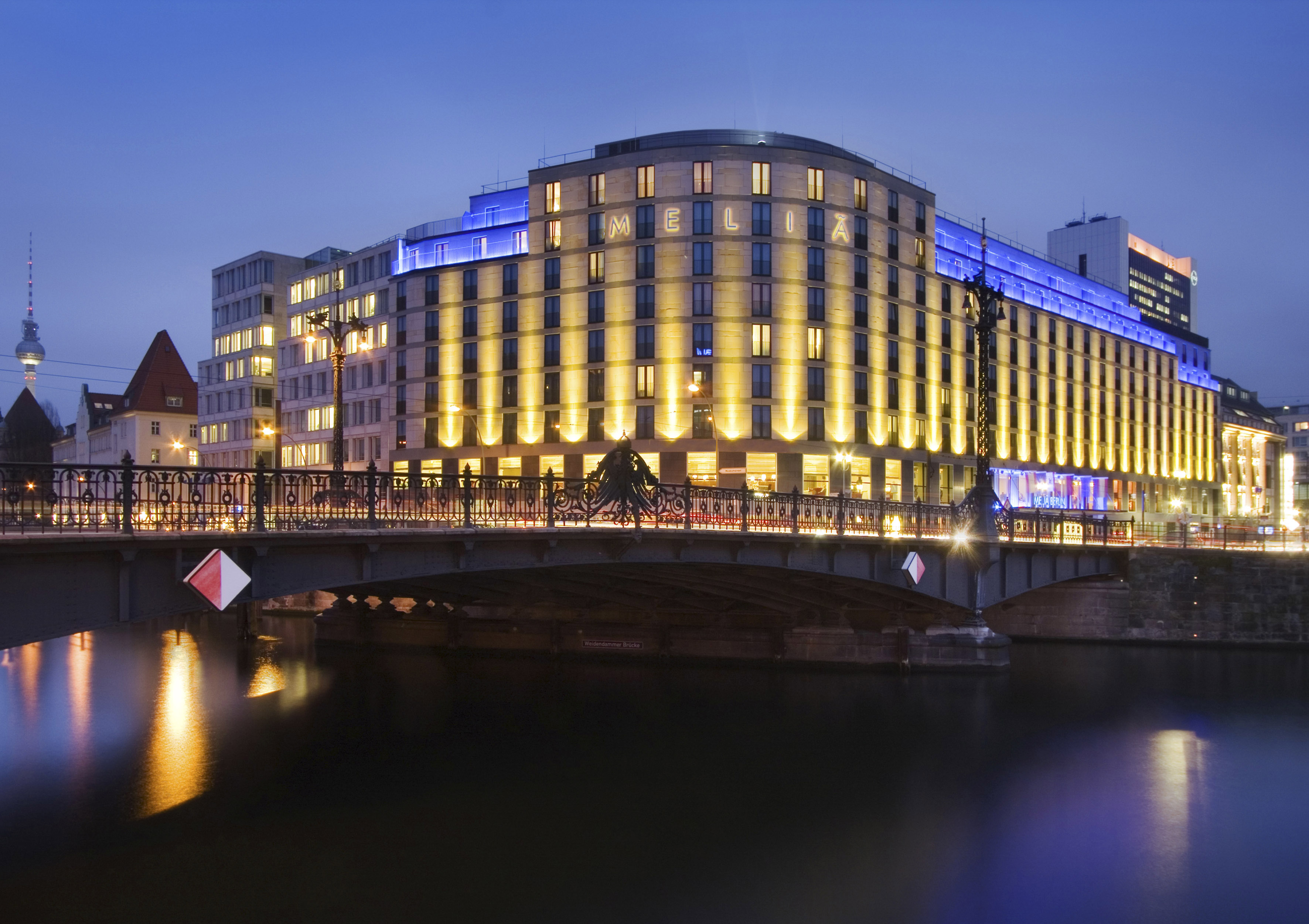 a building with lights on it and a bridge over water
