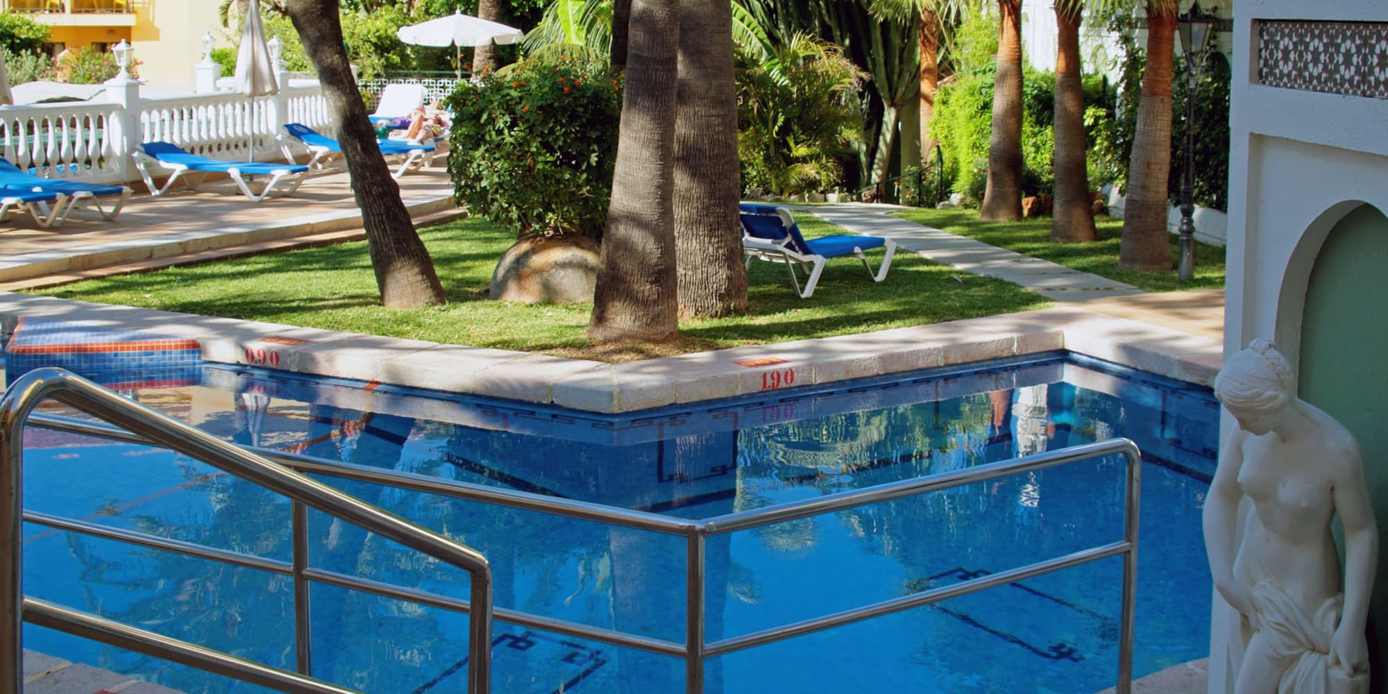 a pool with a metal railing and palm trees