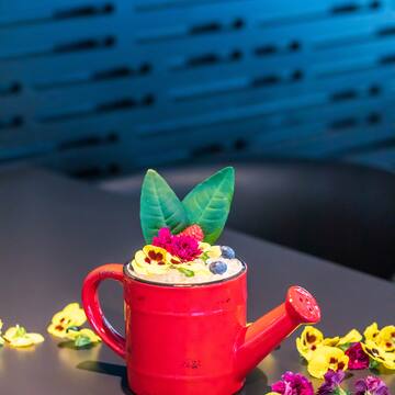 a red watering can with flowers and leaves on top