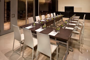 a long table with white chairs and a glass wall
