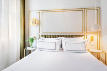 a bed with white sheets and pillows