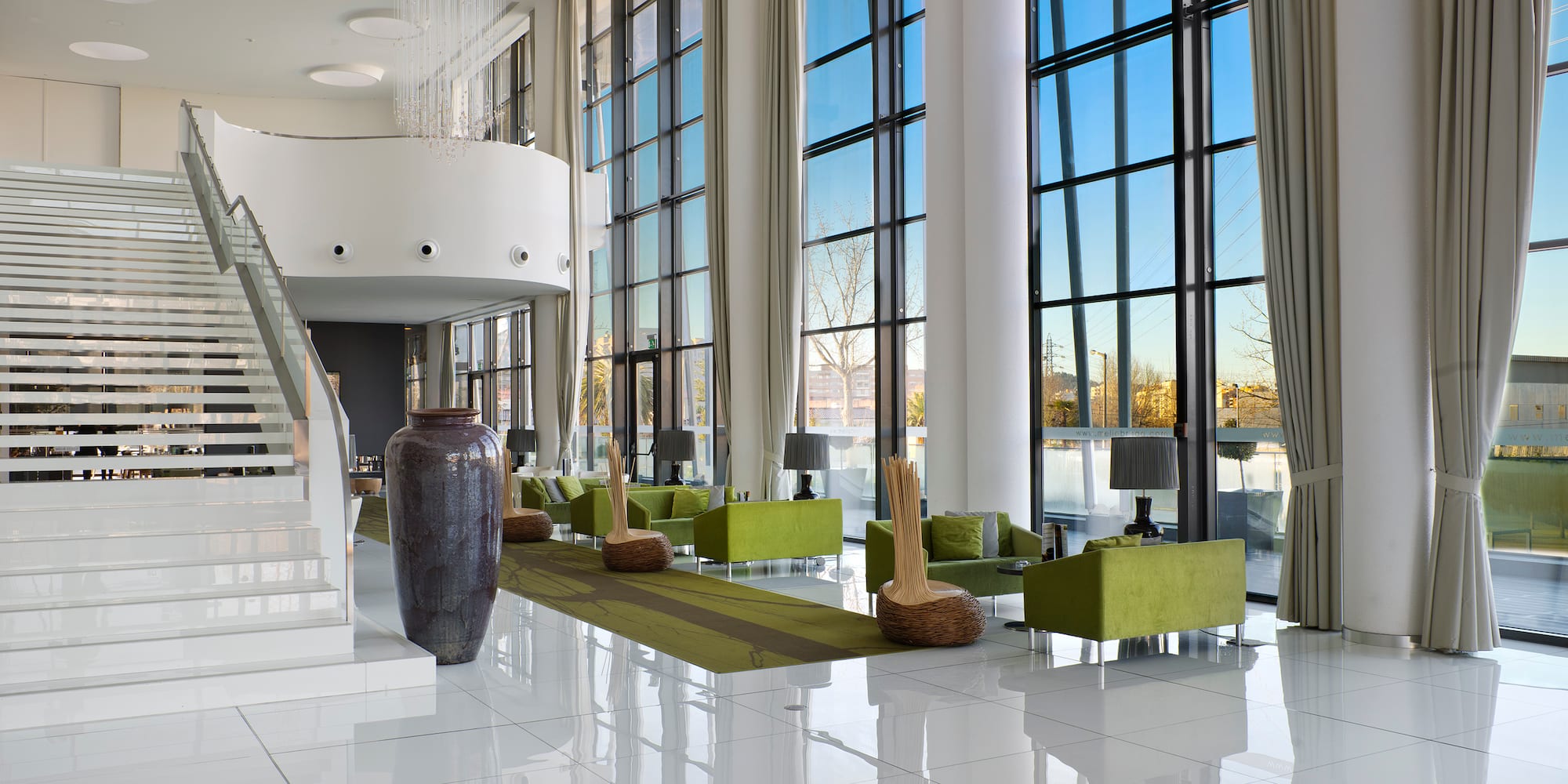 a large white room with green chairs and a staircase