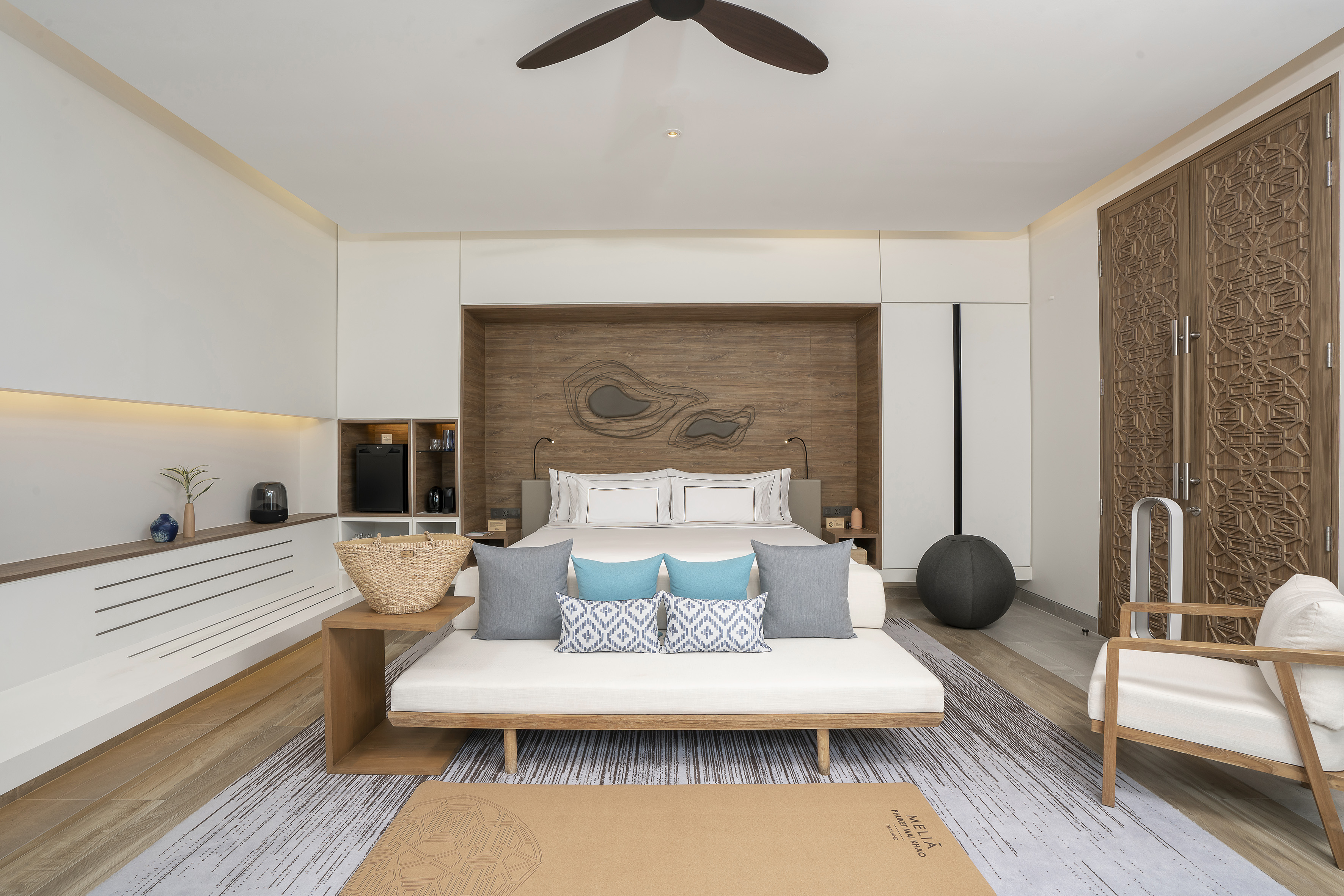 Modern resort bedroom with daybed, wooden headboard, and yoga mat.