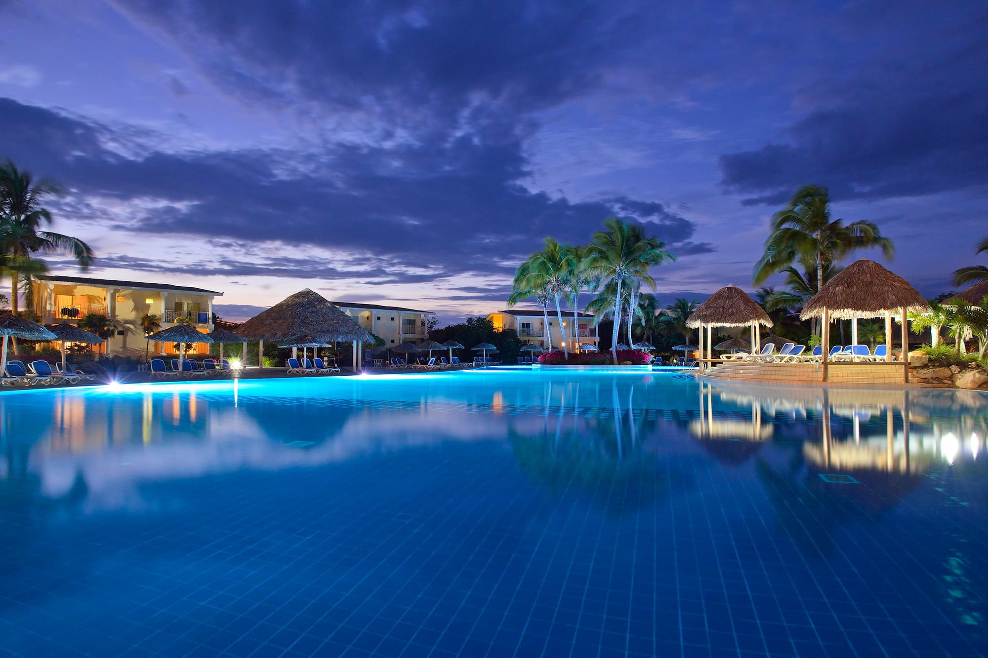 a pool with a building and palm trees