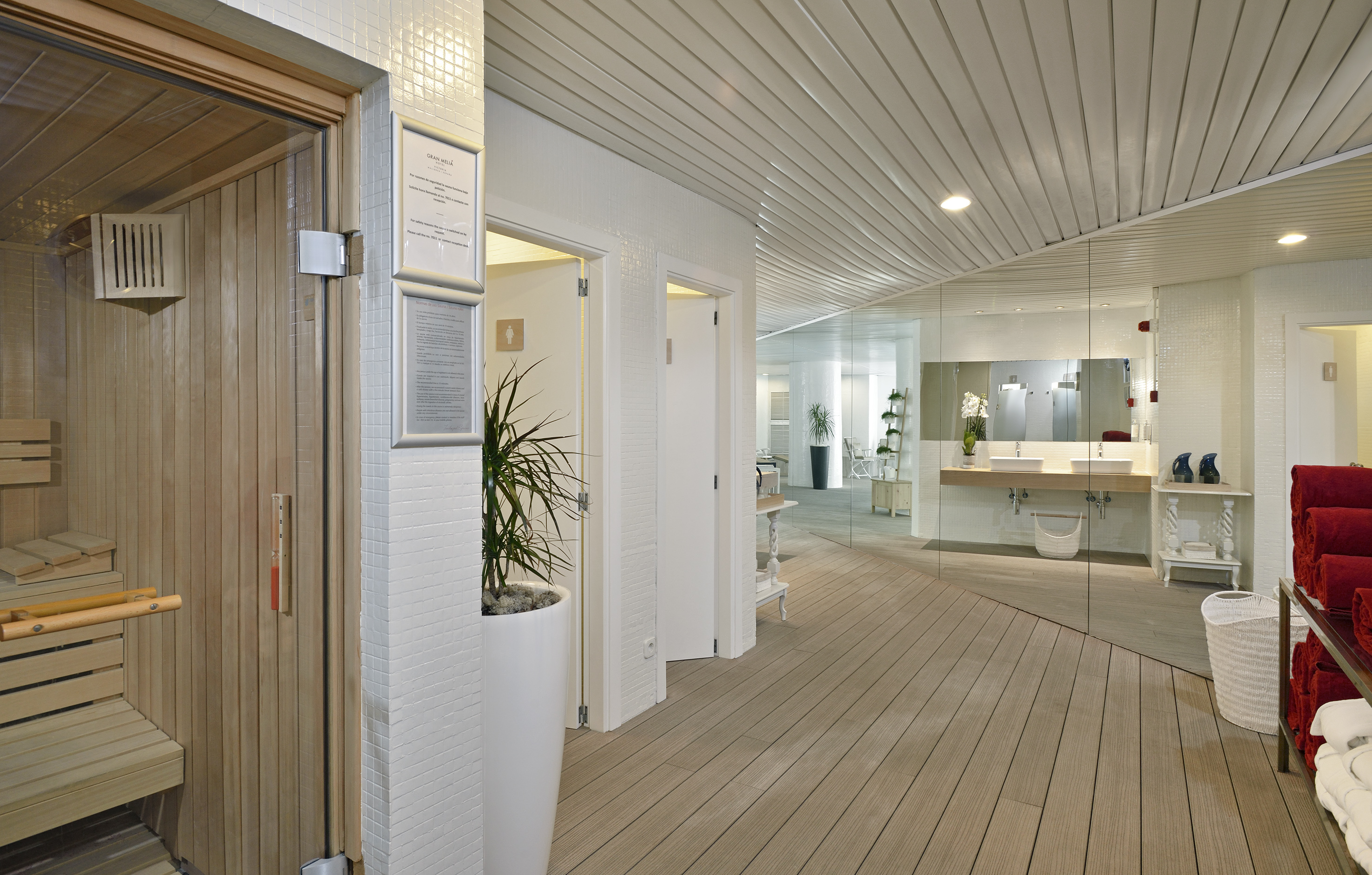 Modern spa area with wooden sauna, white bathroom, and light wood flooring.