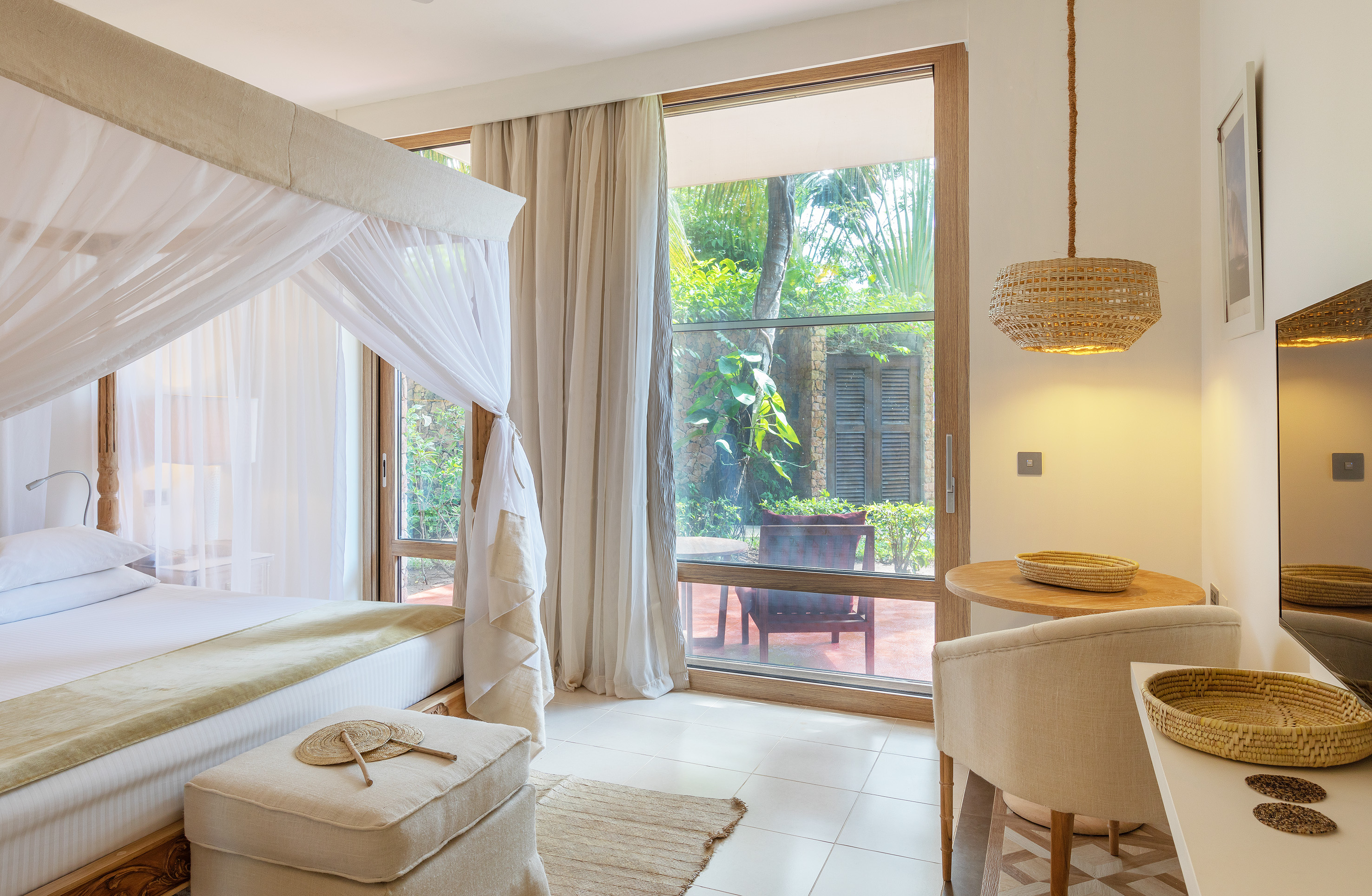 Serene tropical bedroom with a four-poster bed, natural accents, and garden access.