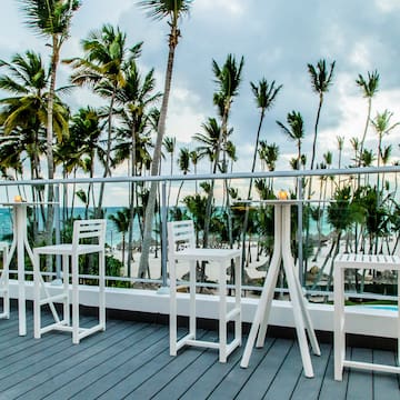 a white table and chairs on a deck overlooking a beach