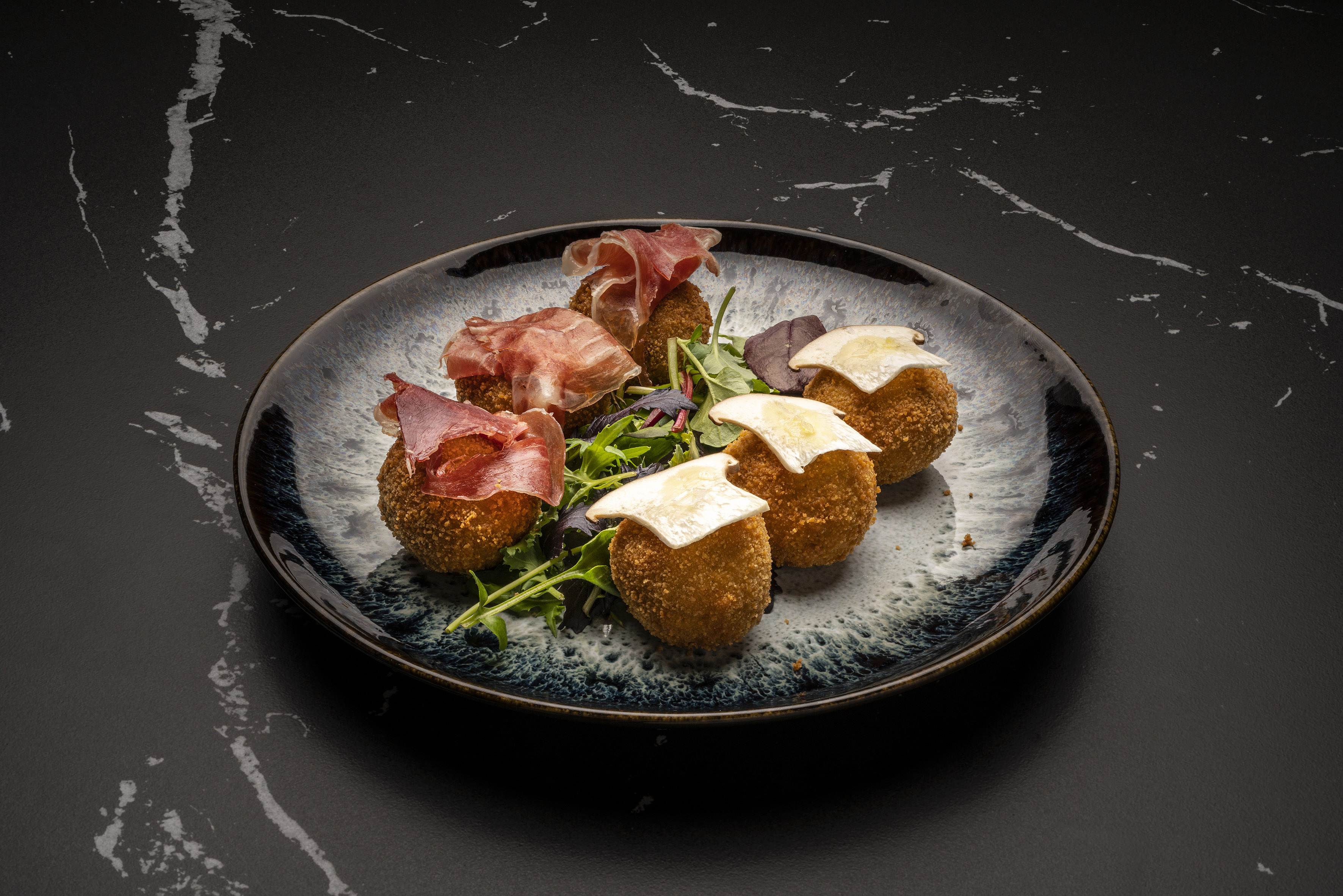 Crispy croquettes with prosciutto and cheese, served with mixed greens.