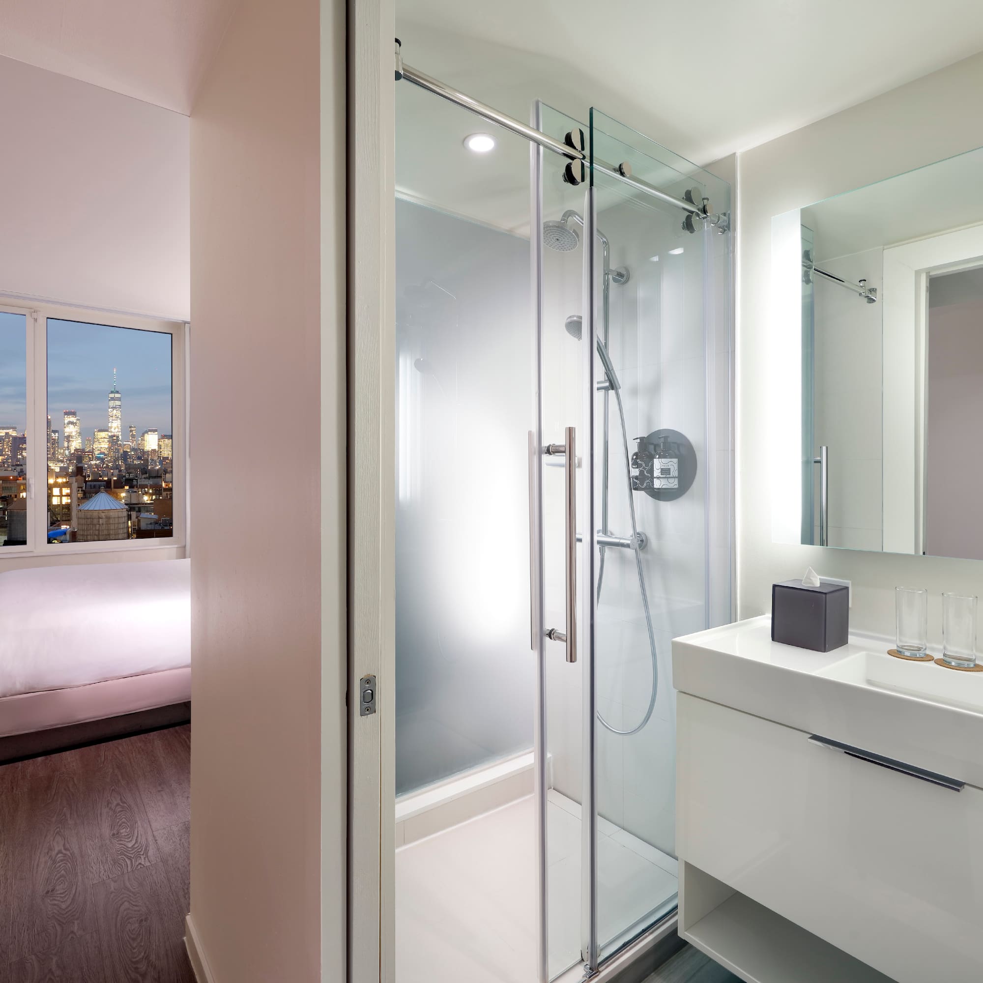 a bathroom with a glass shower and a bed