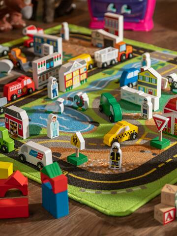 a group of wooden toy cars and buildings on a rug